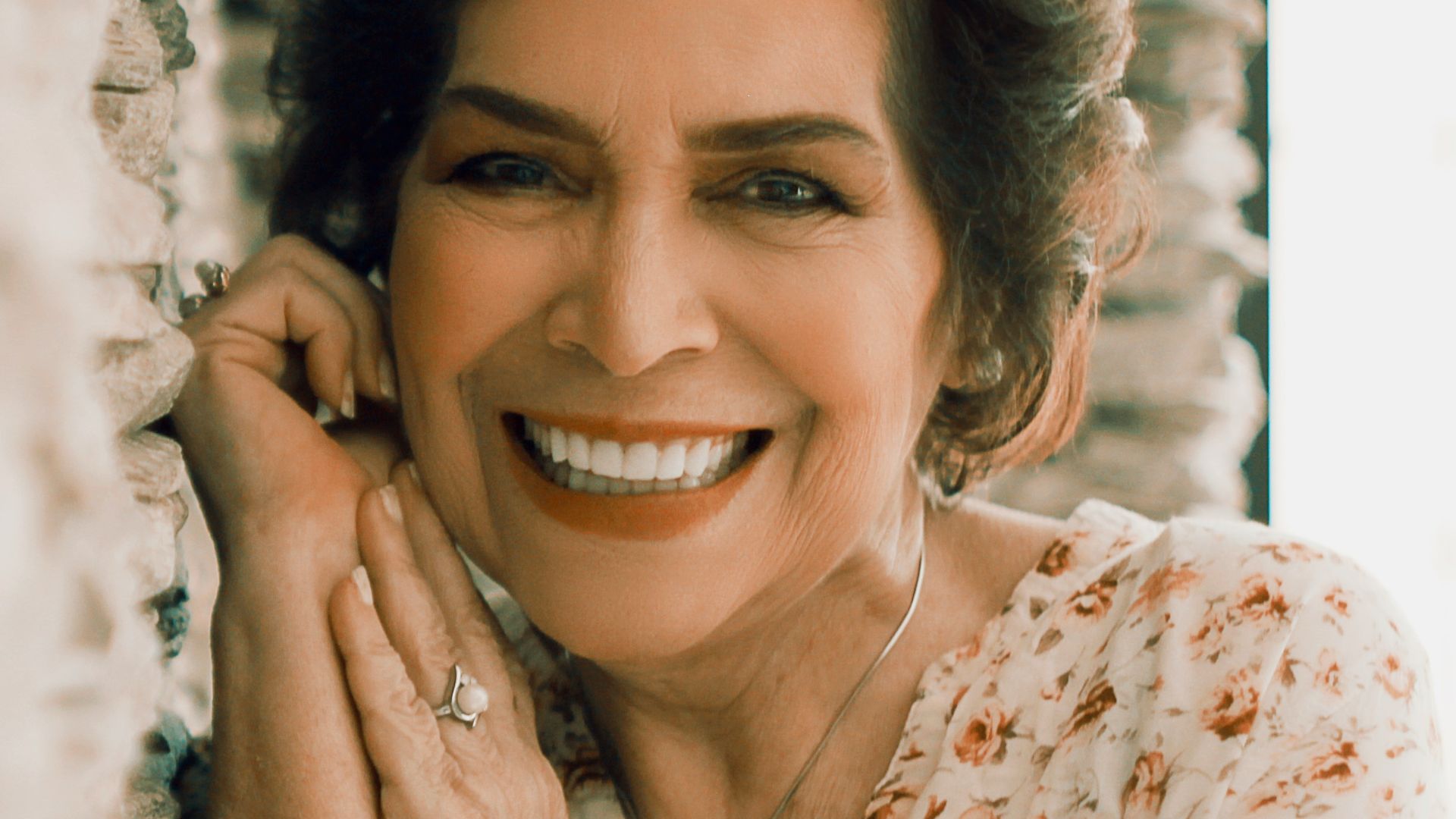 woman in white and orange floral shirt smiling