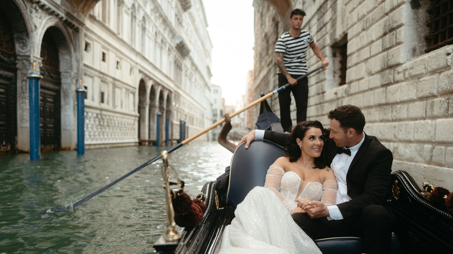 A man and a woman riding a gondola down a street