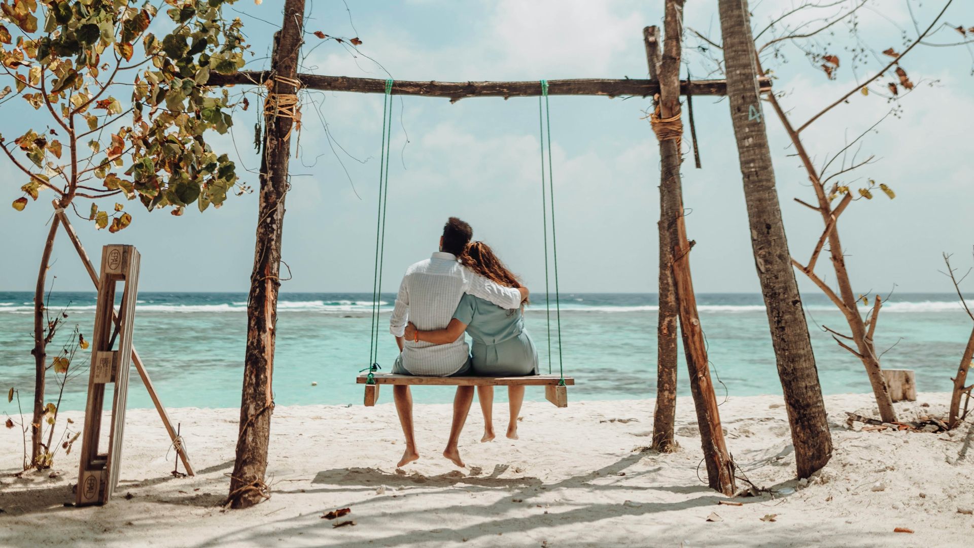 a couple sitting on a bench on a beach