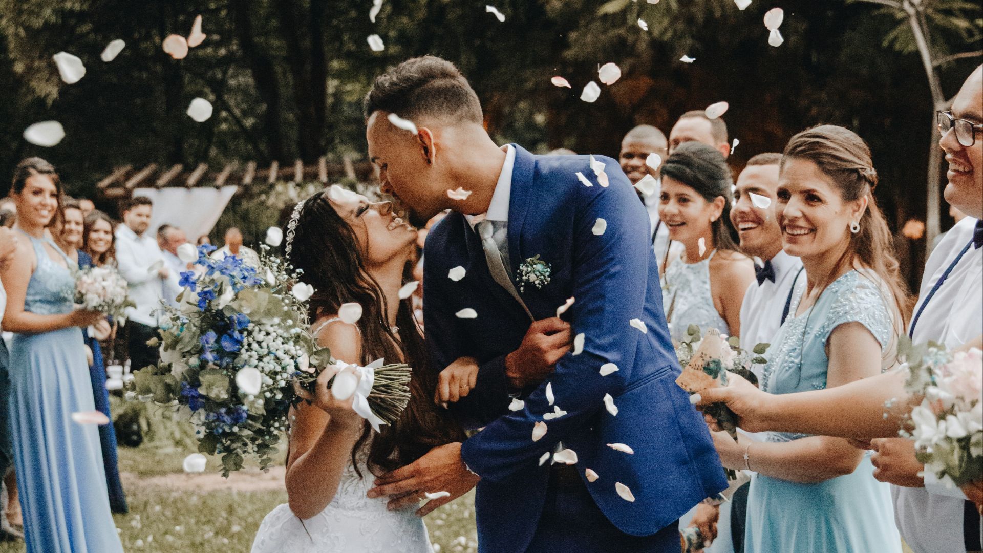 man in blue suit kissing woman in white wedding dress