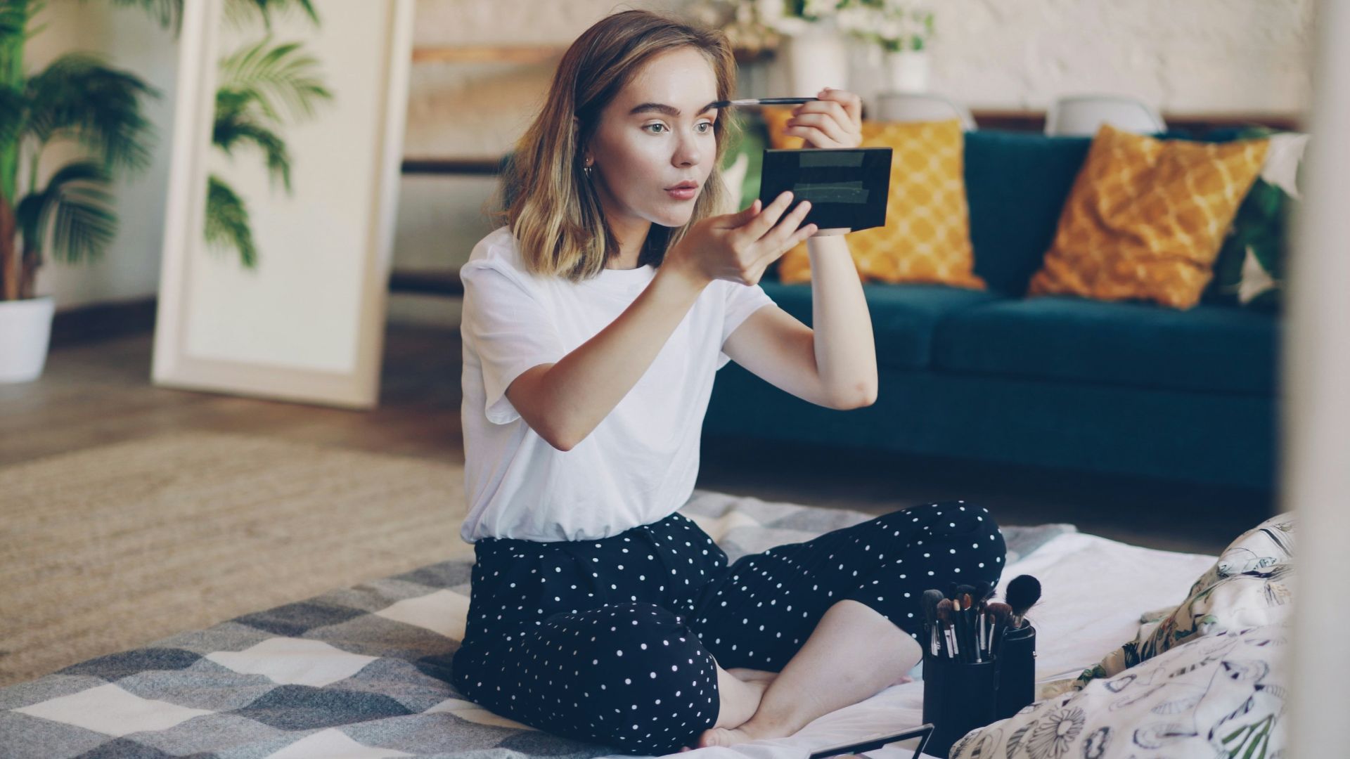 Young woman applying makeup on floor