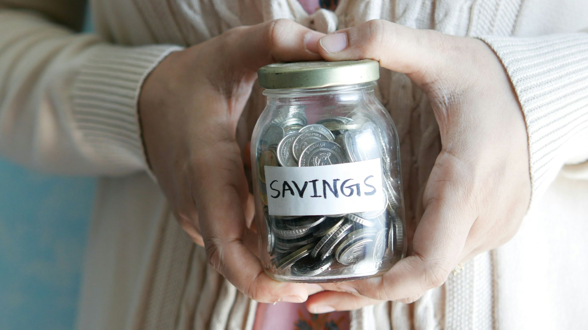 a woman holding a jar with savings written on it