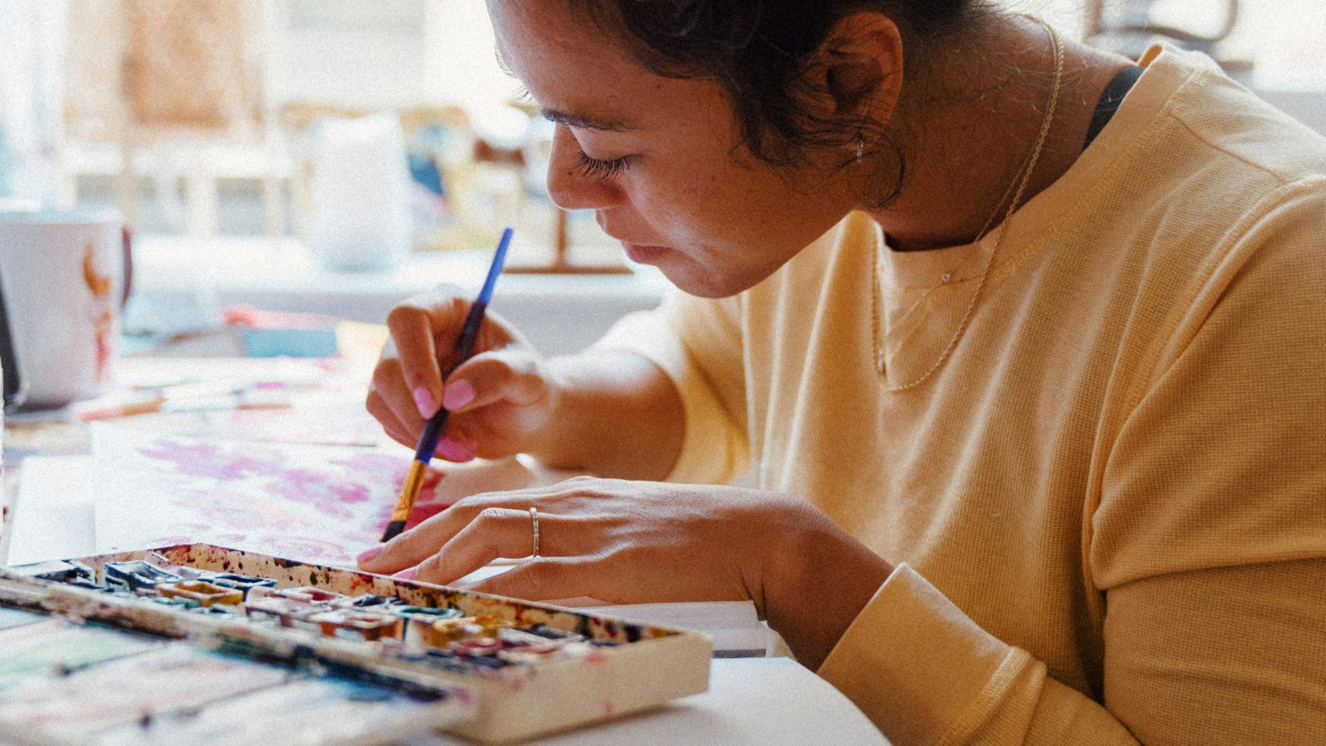 woman in yellow crew neck long sleeve shirt writing on white paper