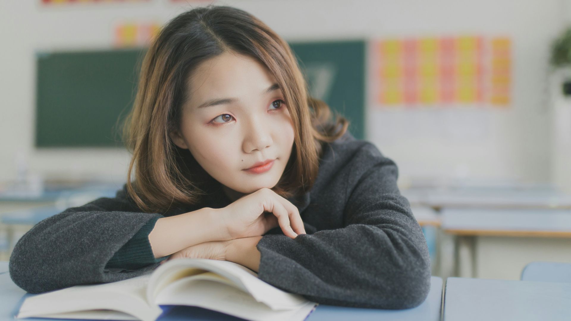 woman in gray dress resting her hands on white table