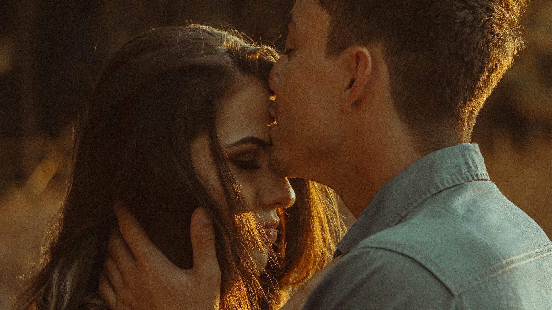 man kissing woman forehead