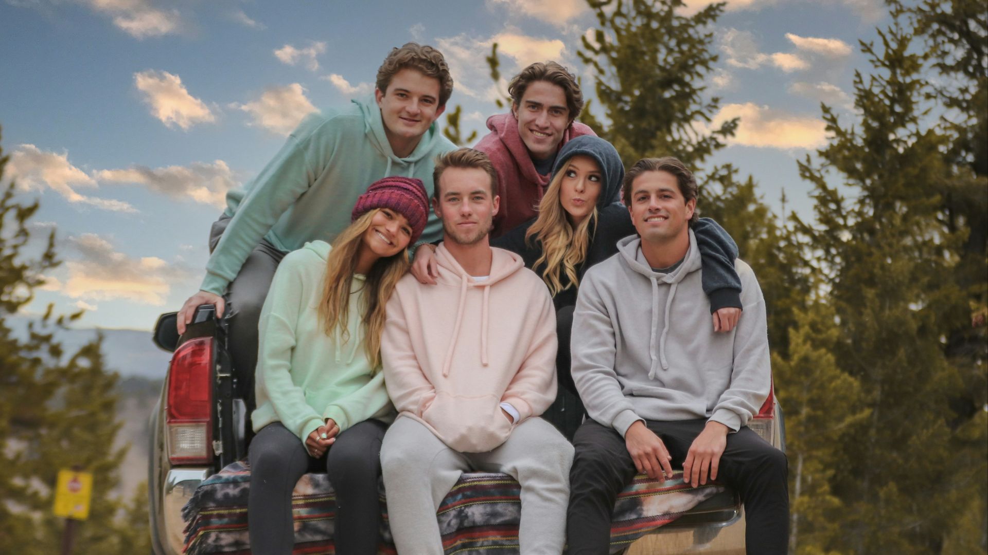 3 women sitting on brown wooden bench during daytime