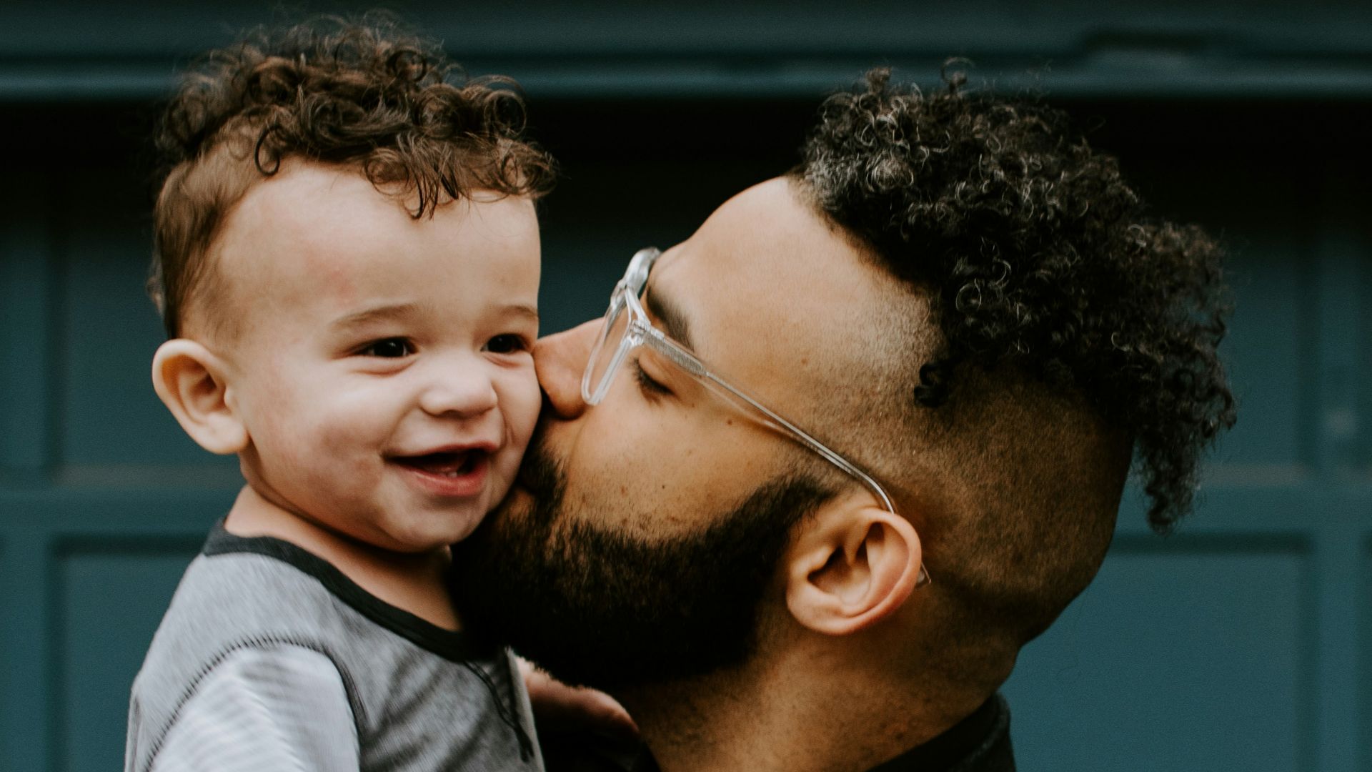 man carrying baby boy and kissing on cheek