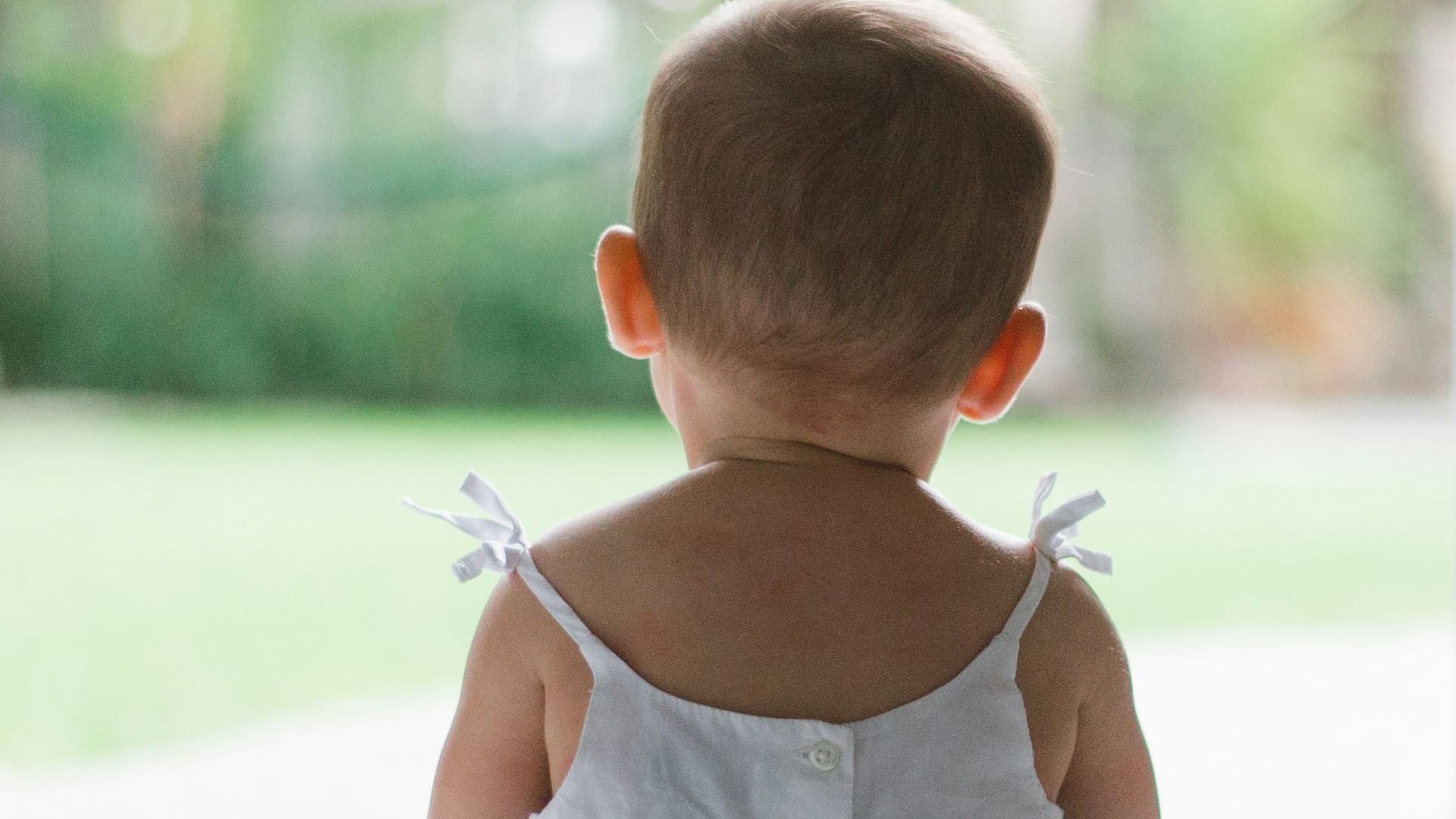 selective focus photo of toddler wearing sleeveless dress sitting on floor