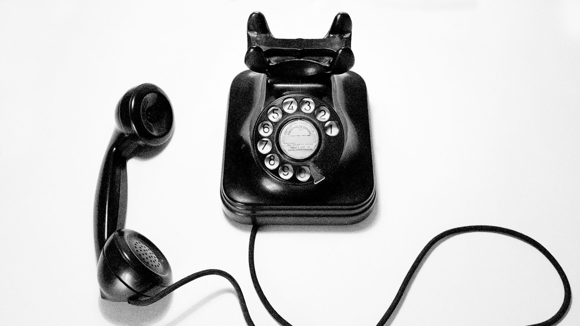 black rotary dial phone on white surface