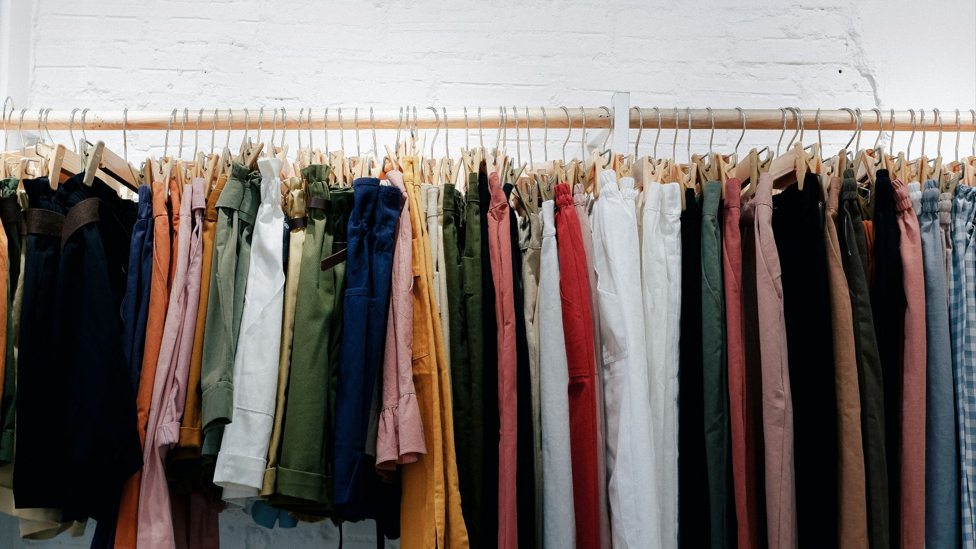 assorted-color clothes lot hanging on wooden wall rack