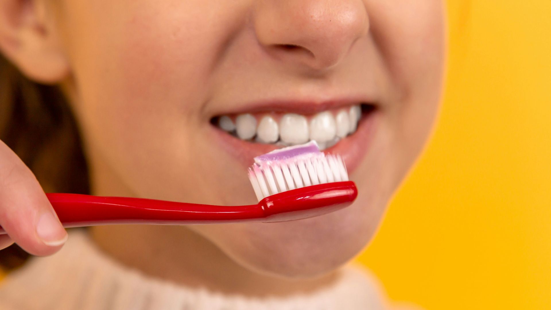 girl with red and white toothbrush in mouth