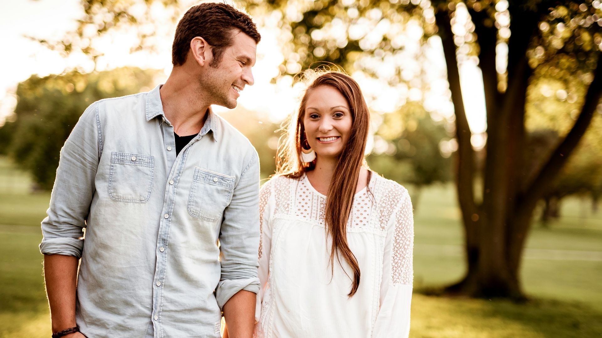 man holding hand of woman standing near tree