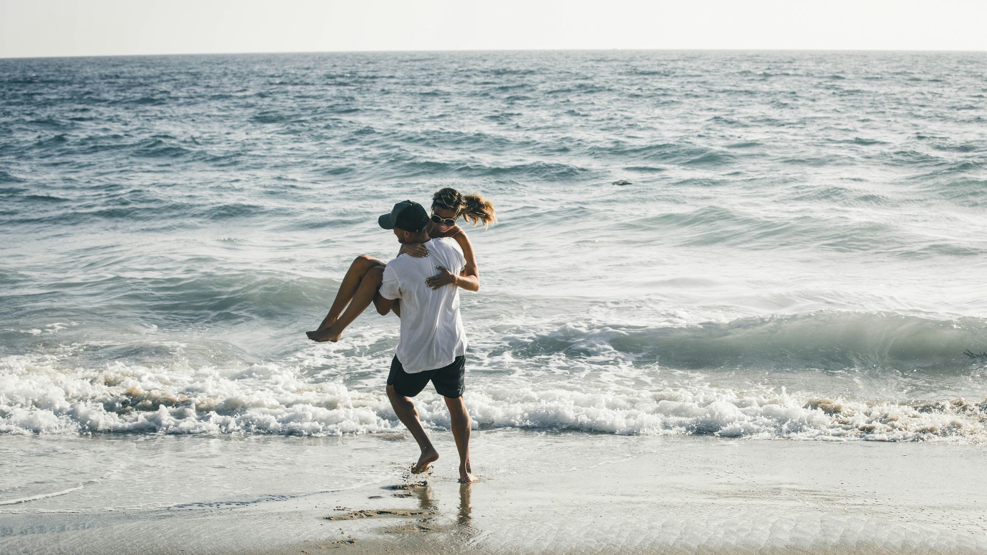 man carrying woman on seashore