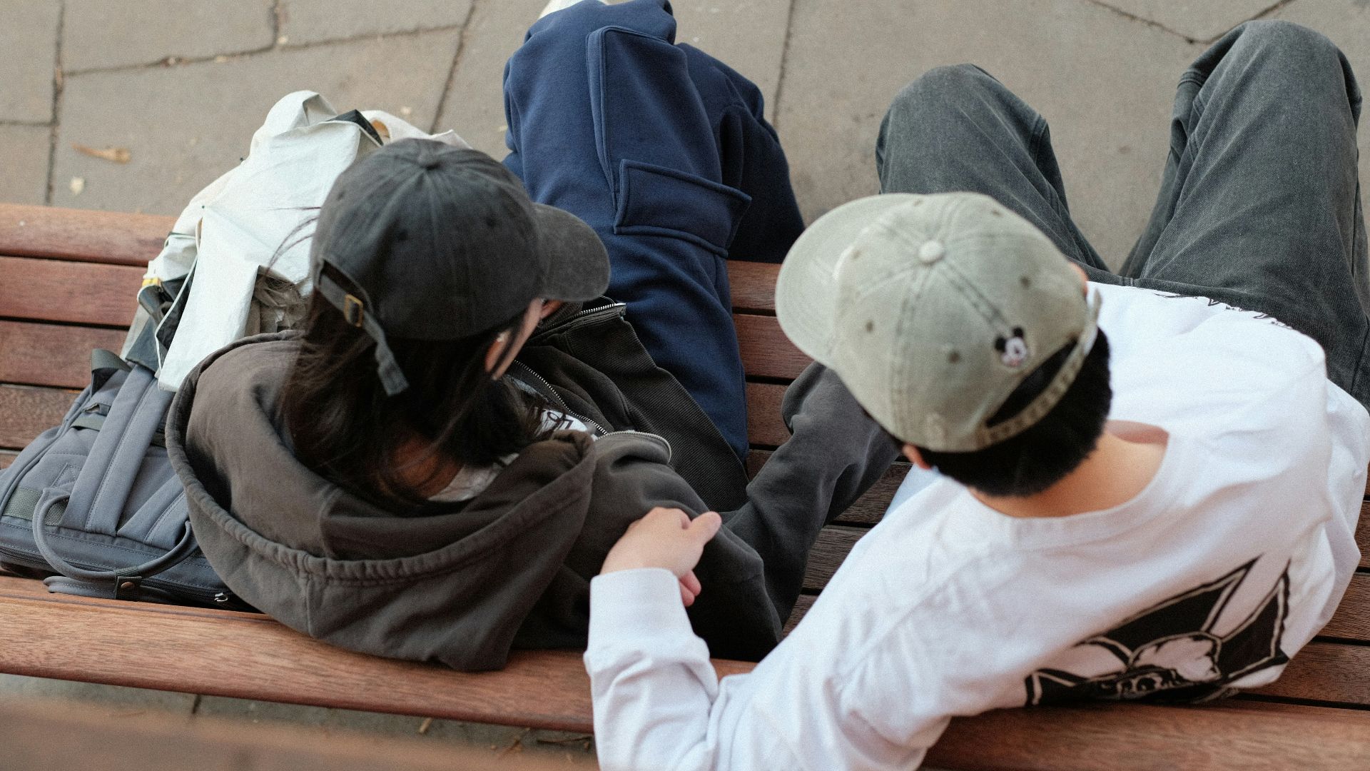 A group of people sitting on top of a wooden bench