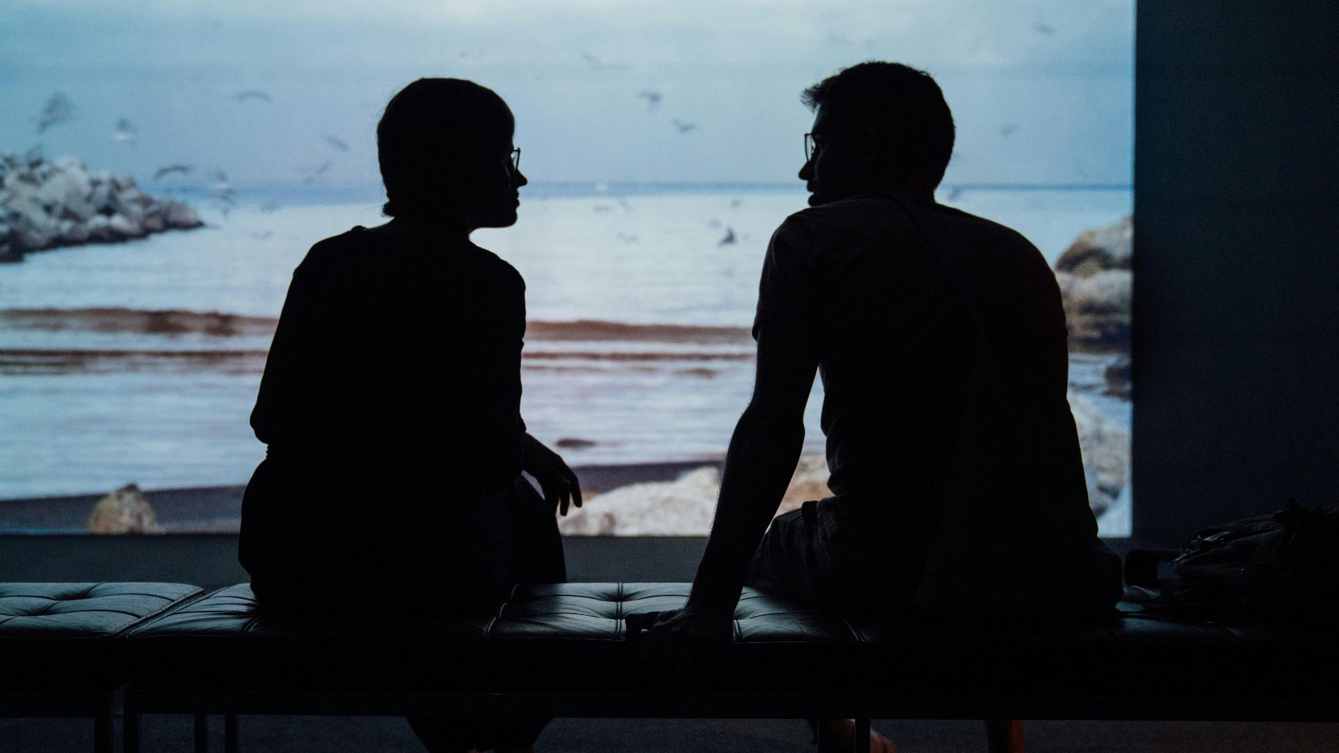 silhouette of man and woman sitting on ottoman