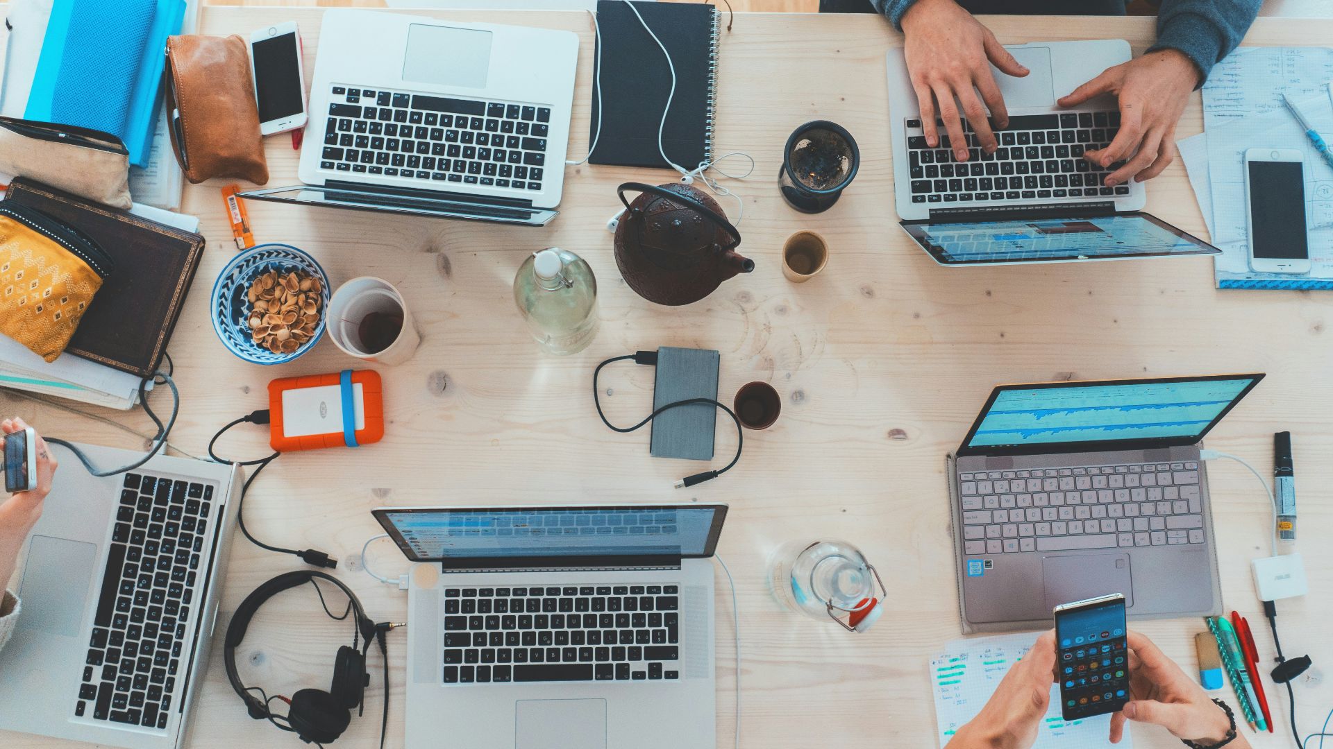 people sitting down near table with assorted laptop computers