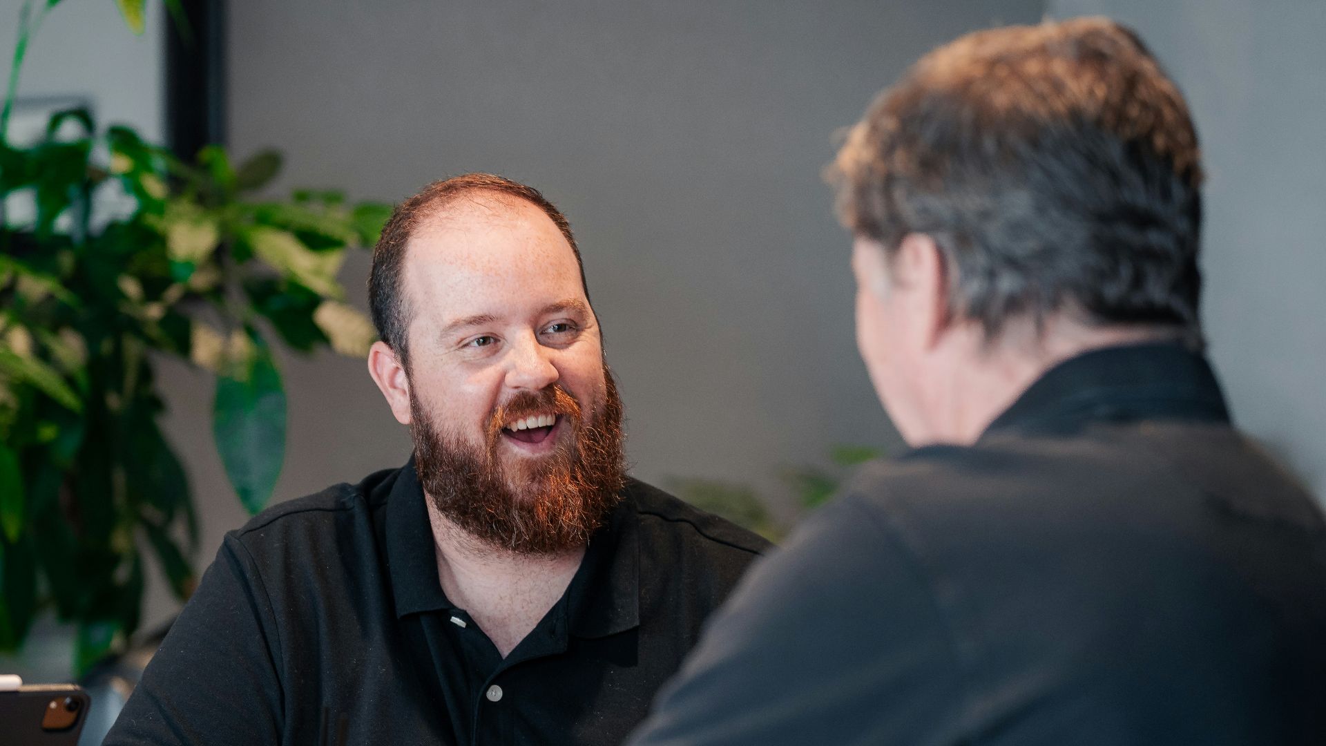 two men sitting at a table talking to each other
