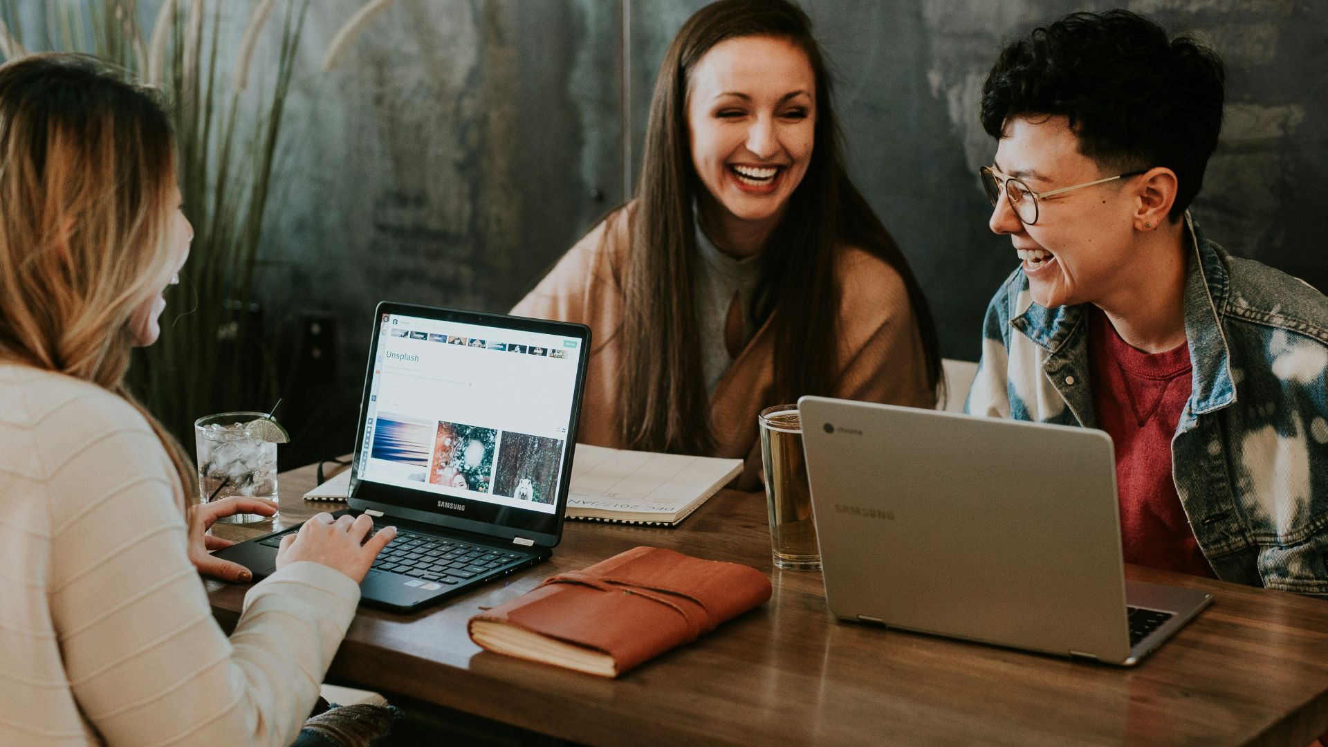 three people sitting in front of table laughing together