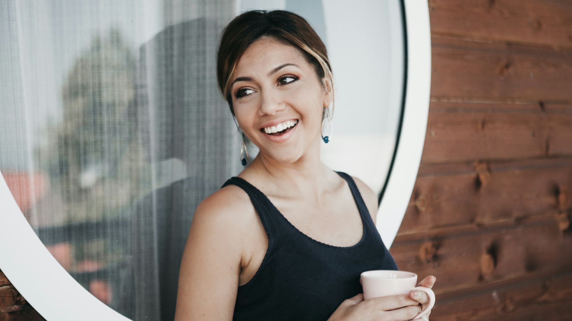 woman wearing black tank top holding mug