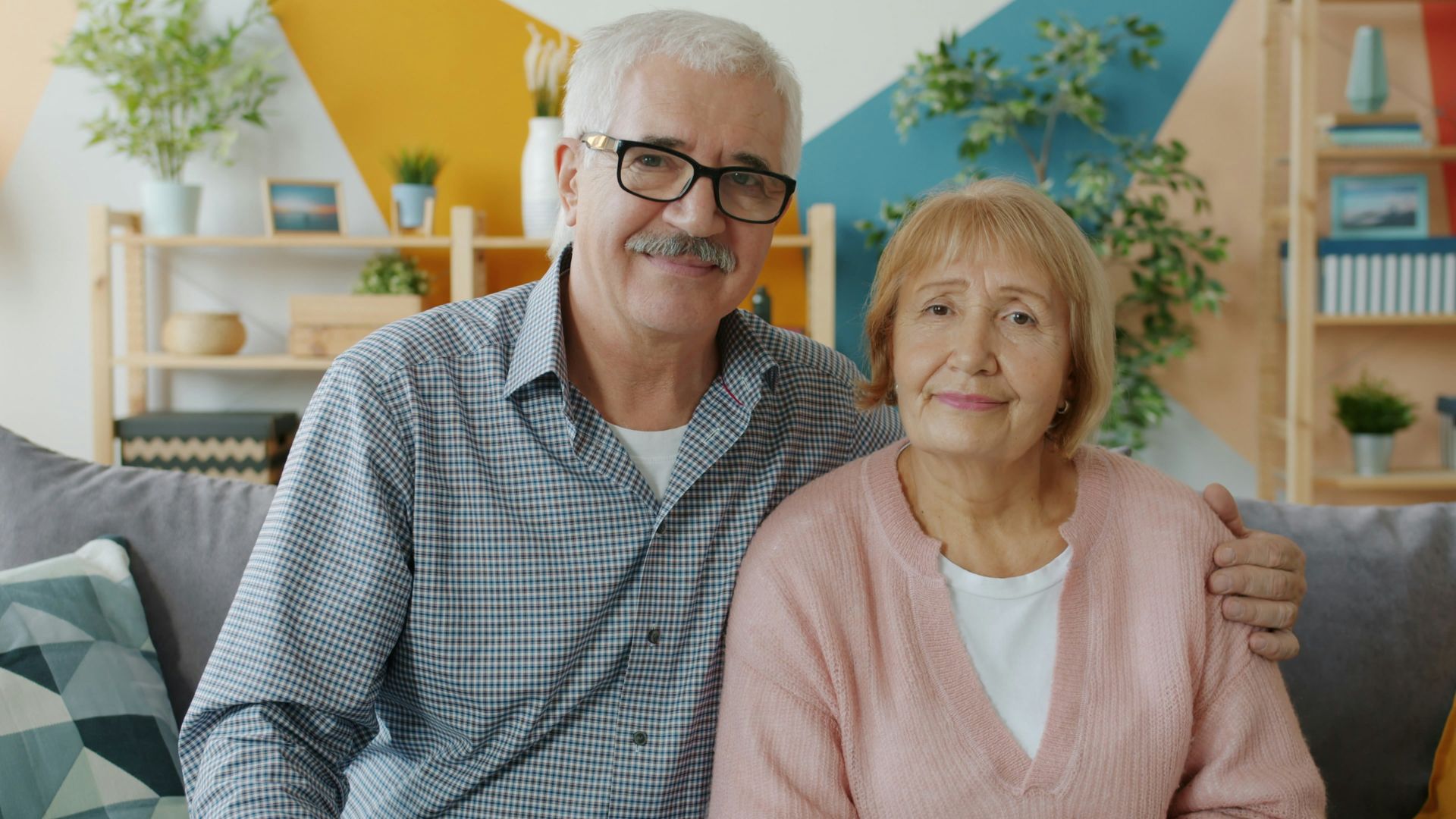 Elderly couple smiling while sitting on a couch.