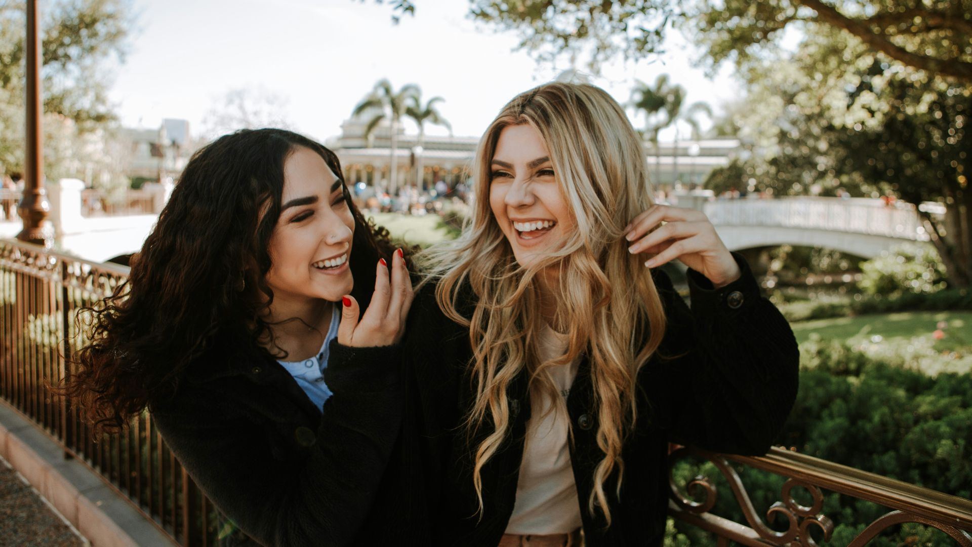 2 women smiling and standing near trees during daytime