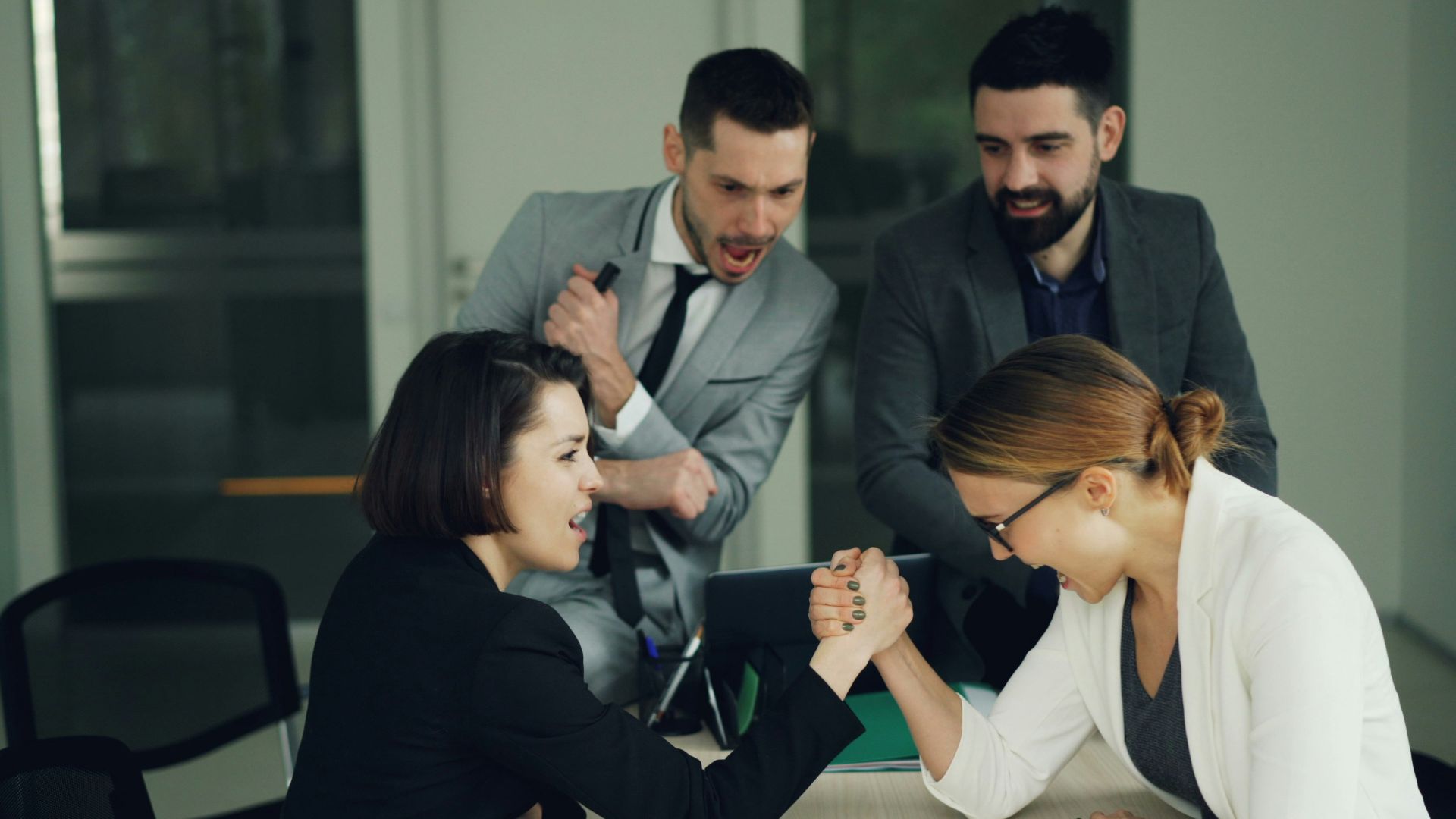 Two women arm wrestling at a table