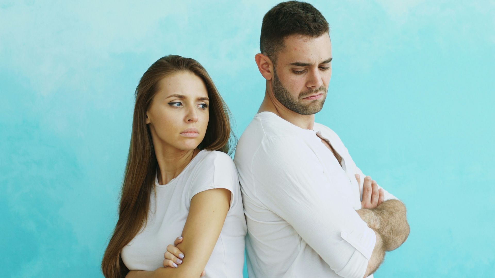 Couple standing back to back with arms crossed