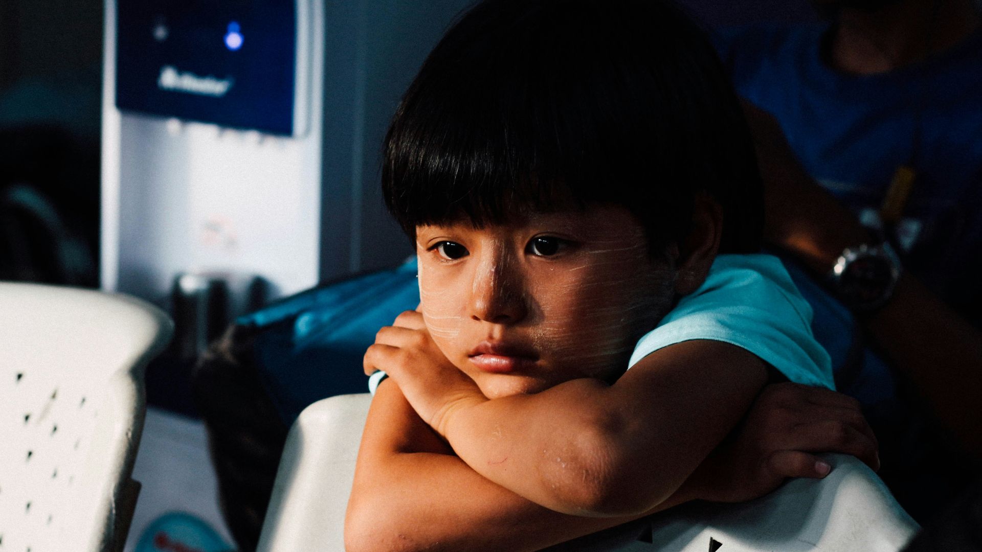 boy leaning on white chair