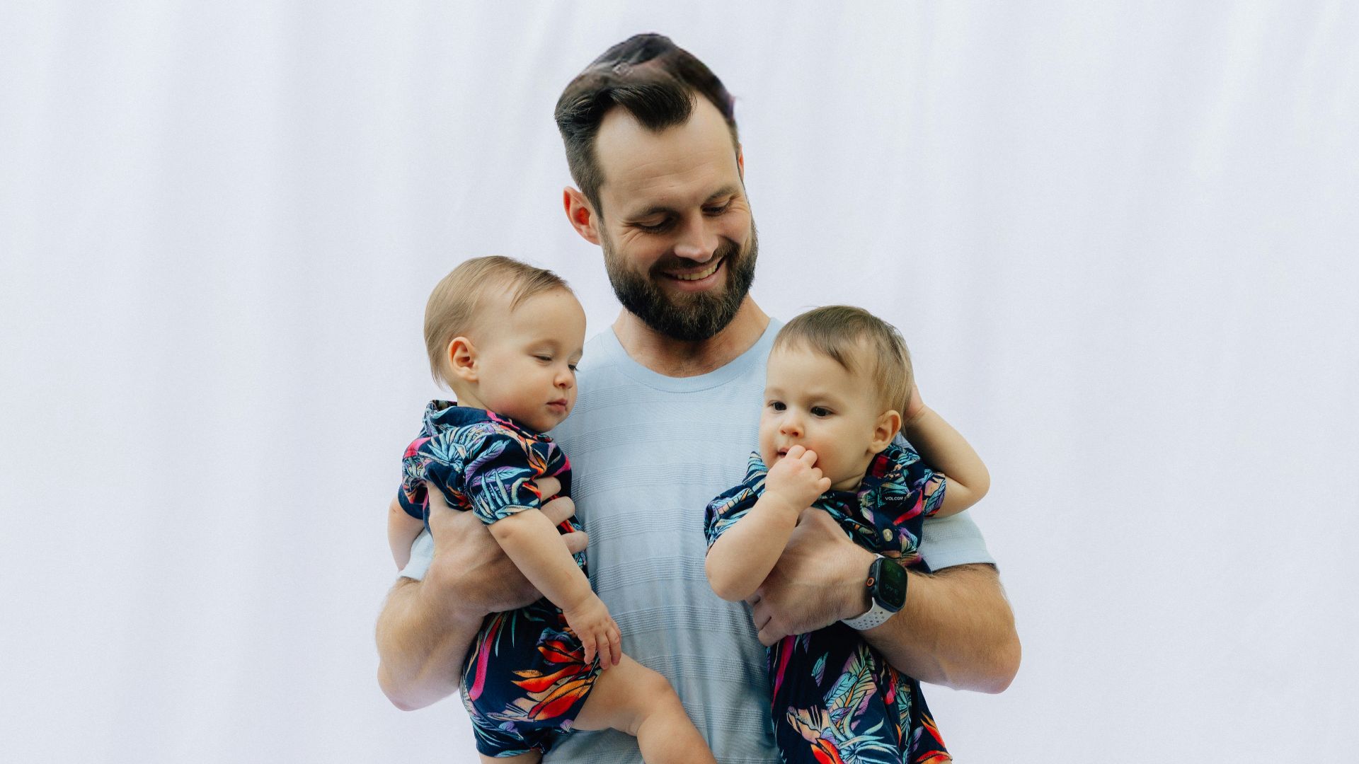 Father holding his two babies in matching outfits
