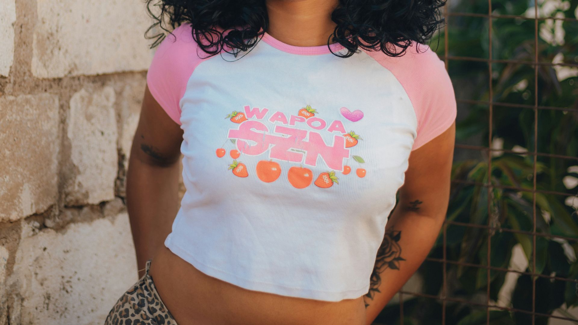 A young woman wearing a crop top and sunglasses.