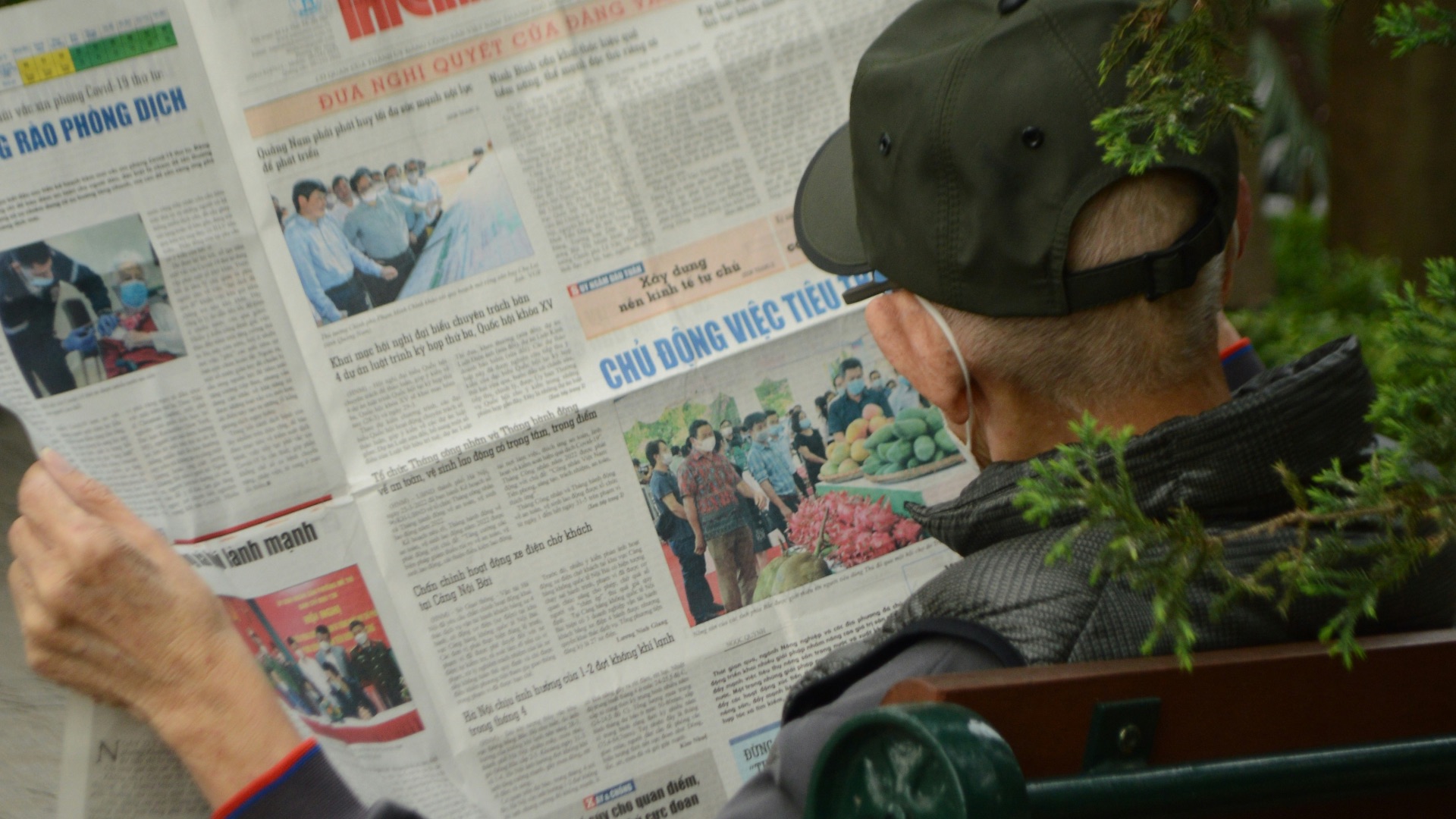 A man sitting on a bench reading a newspaper