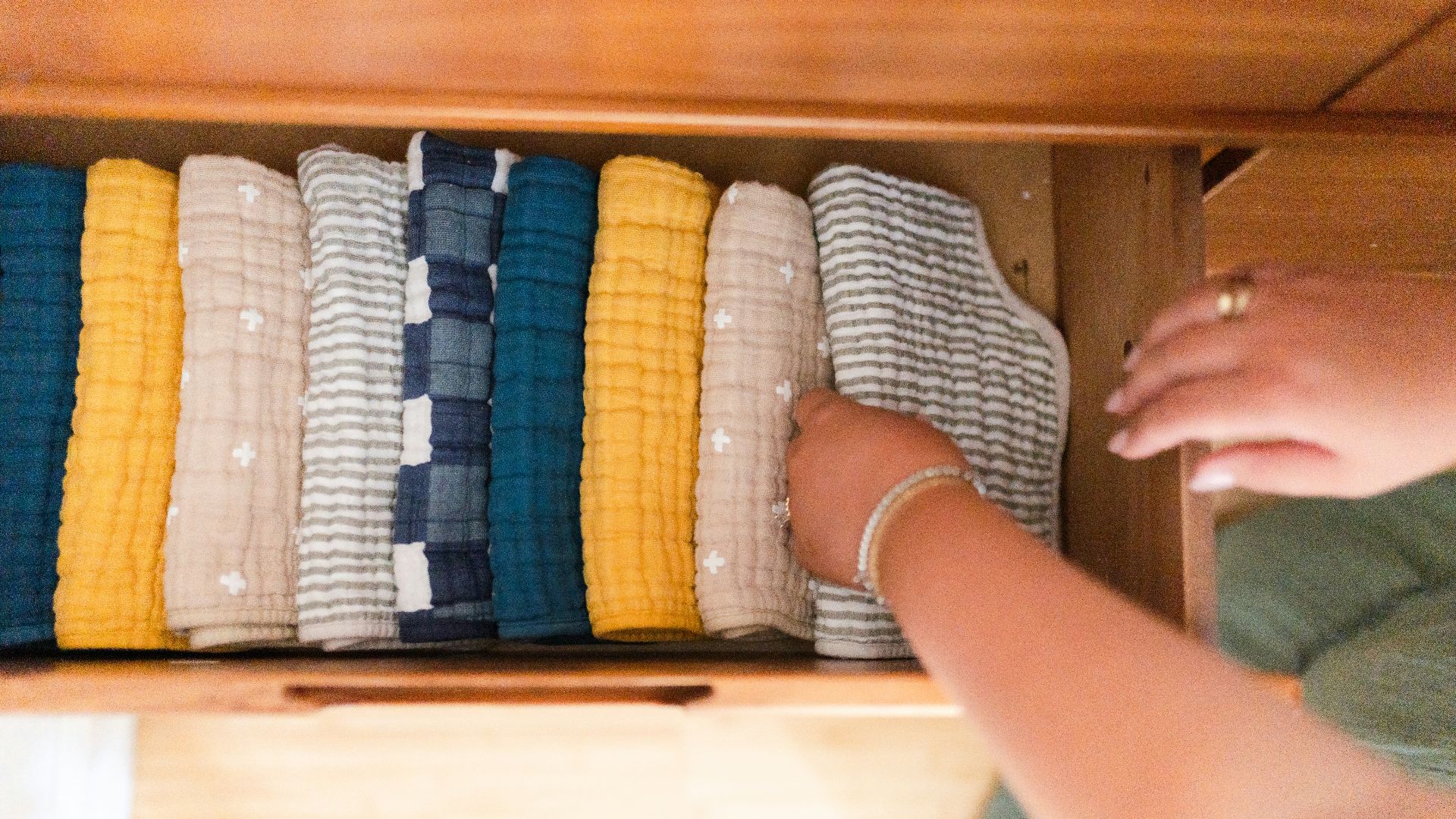 a woman is looking at a drawer full of sweaters