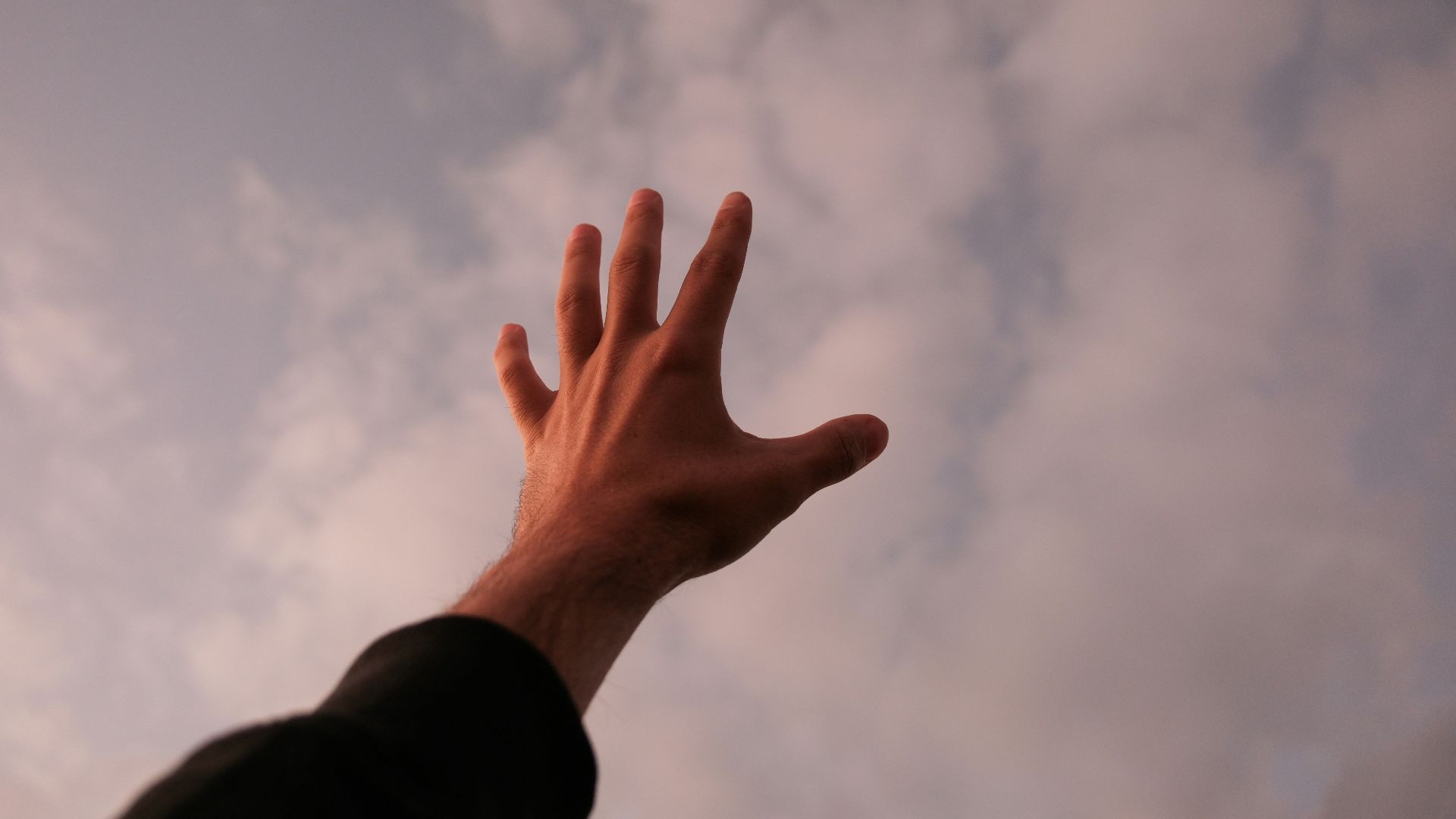 a person's hand reaching up into the sky