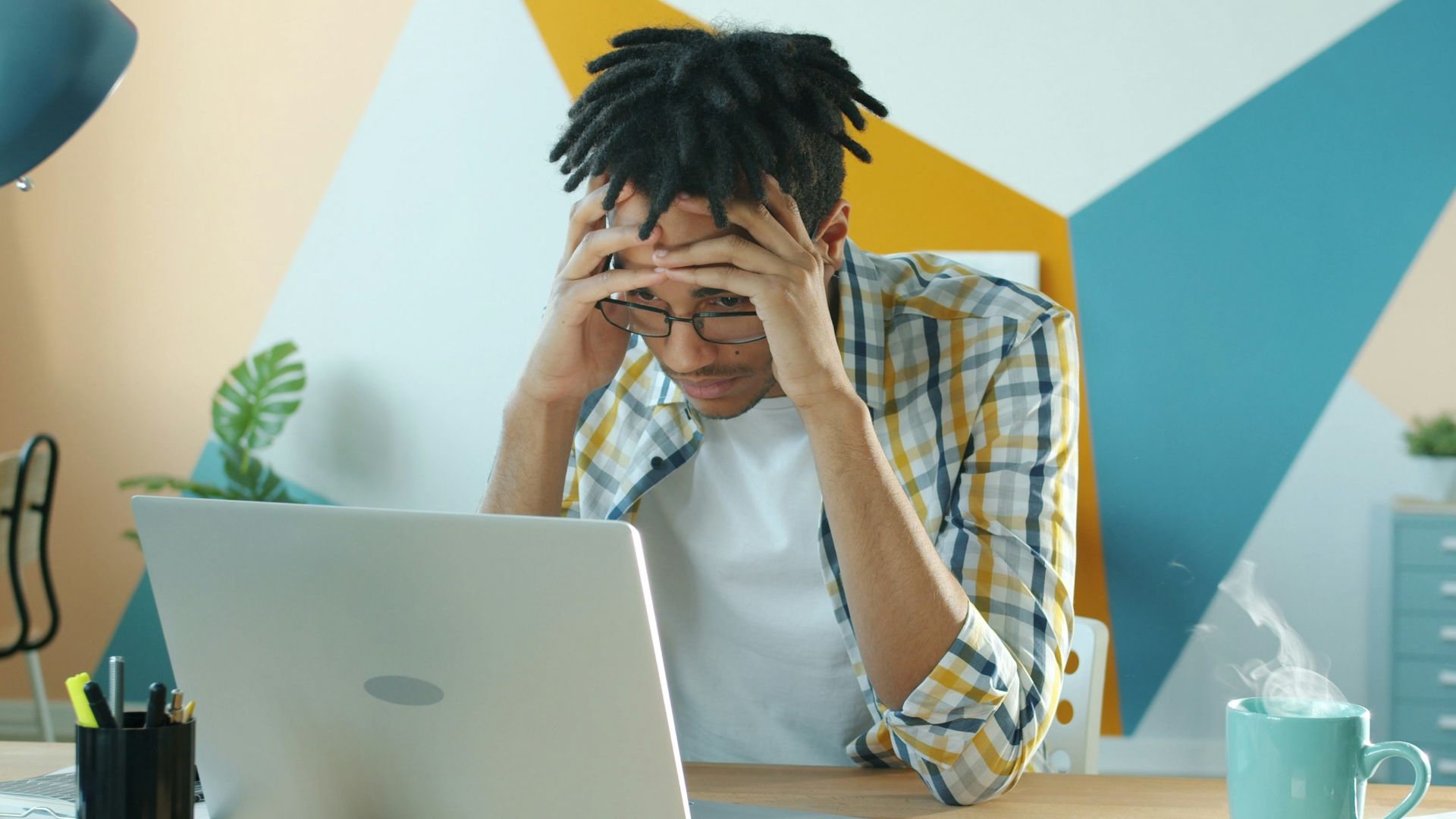 Man holding head in frustration at desk with laptop.