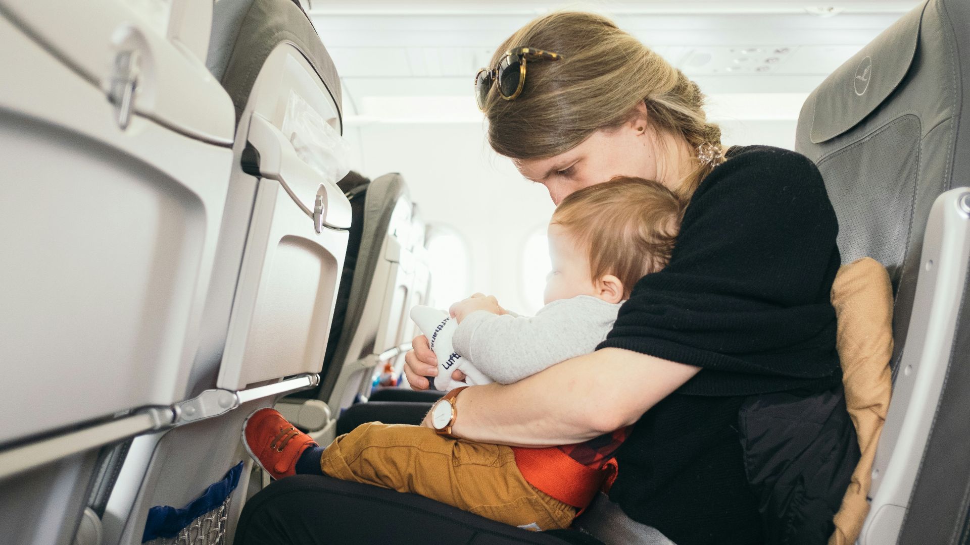 woman carrying baby while sitting on gray seat