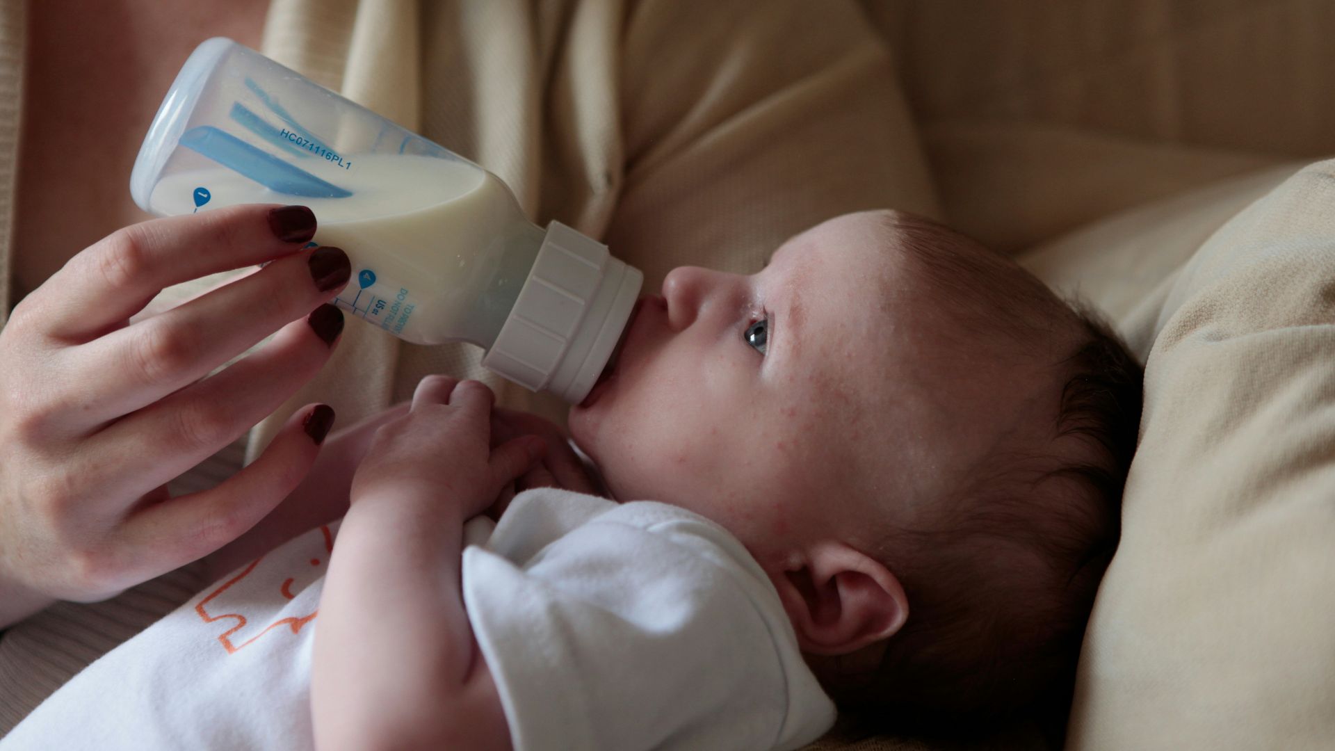 a woman feeding a baby with a bottle of milk