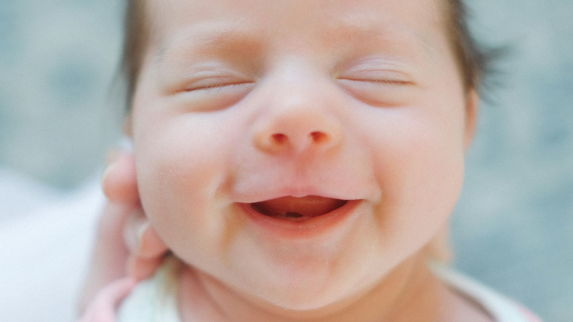 a close up of a baby smiling with its eyes closed