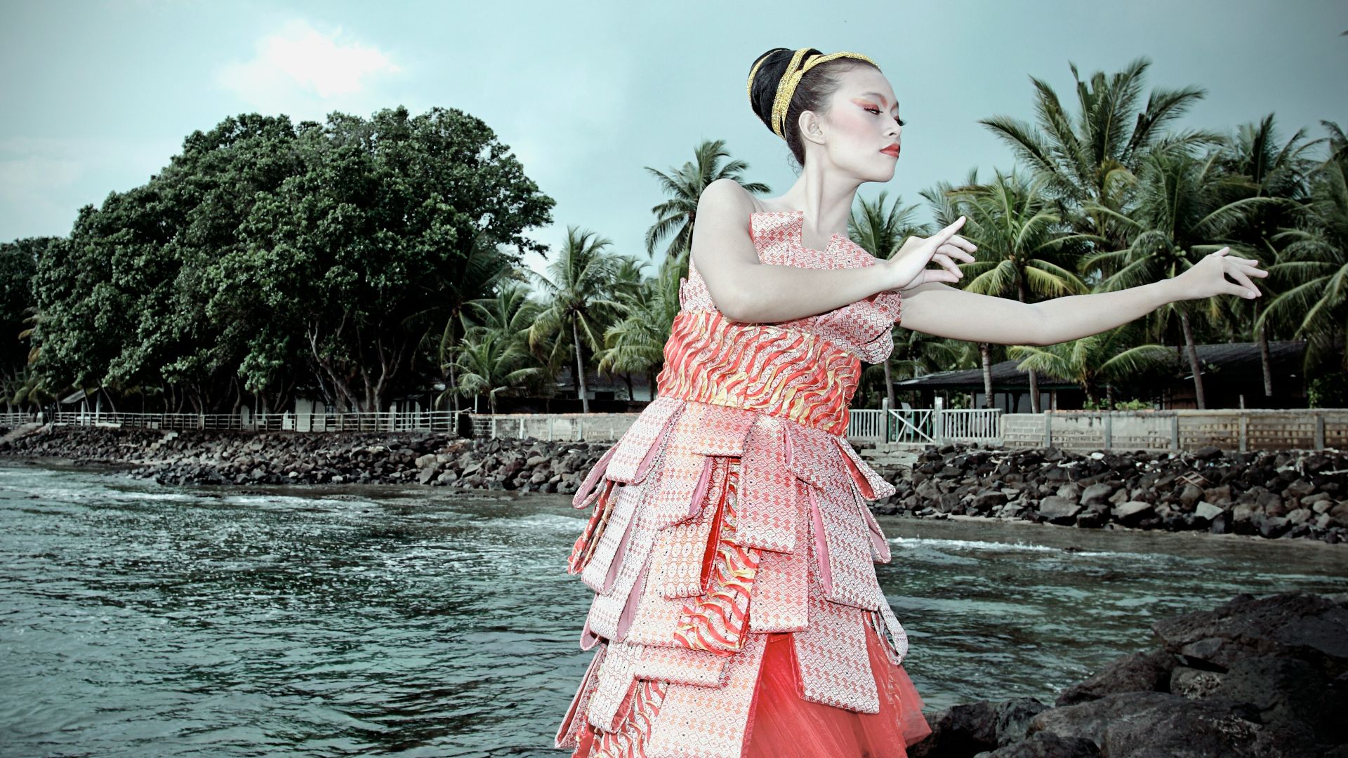 a woman in a dress standing on rocks near the water