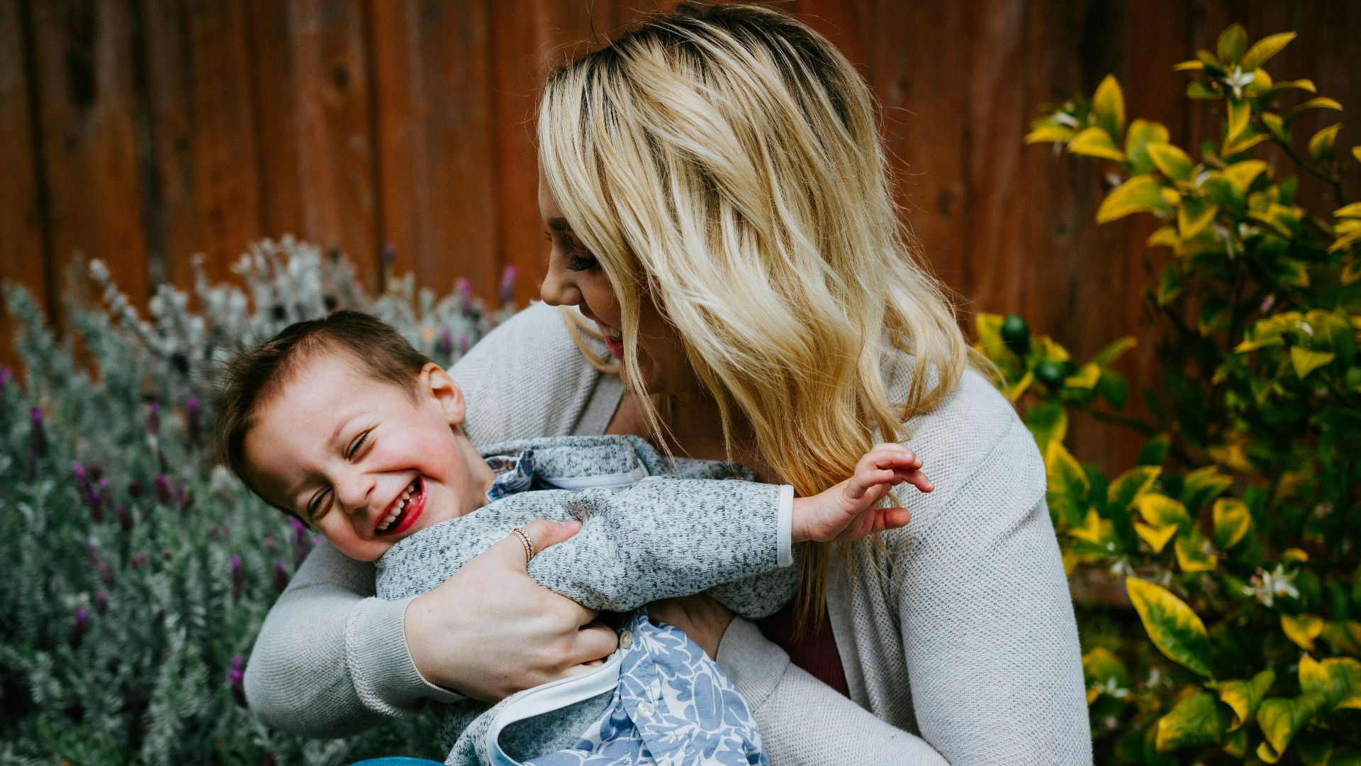 woman in gray sweater carrying girl in blue denim jacket