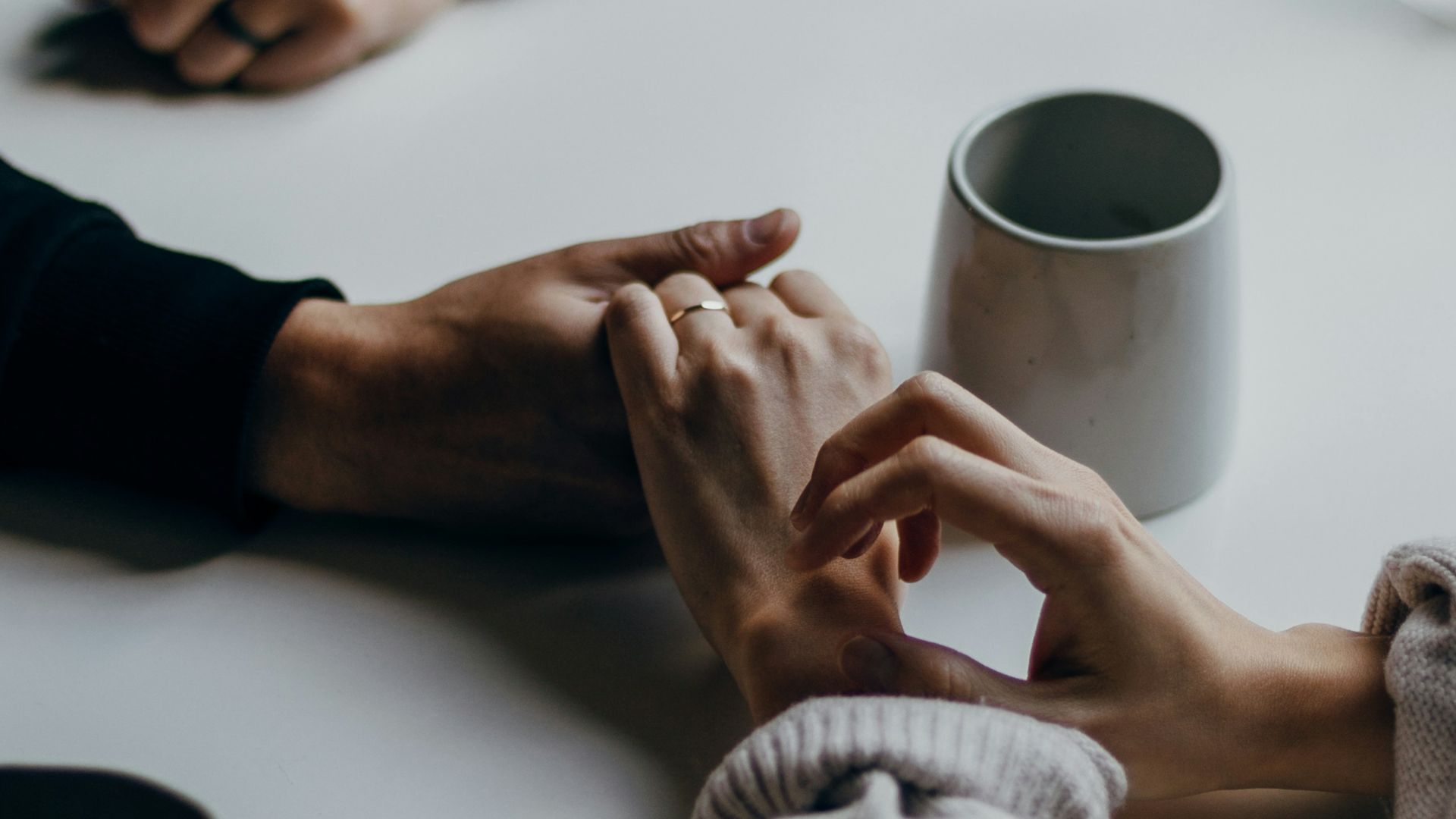 person in black long sleeve shirt holding white ceramic mug