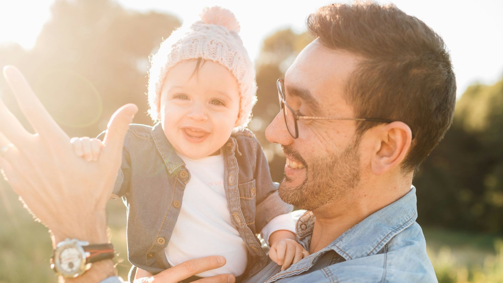 man in blue denim jacket carrying girl in white sweater during daytime