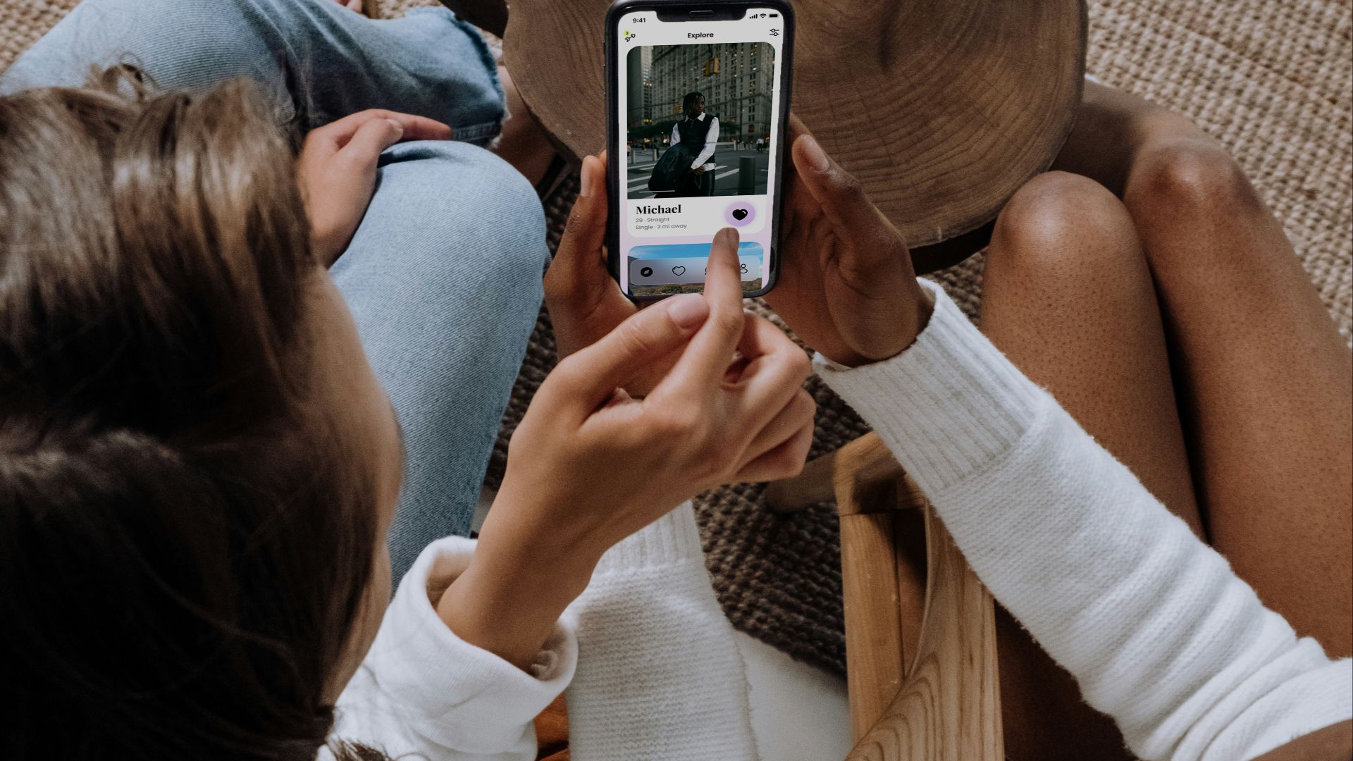 two women sitting on a couch looking at a cell phone