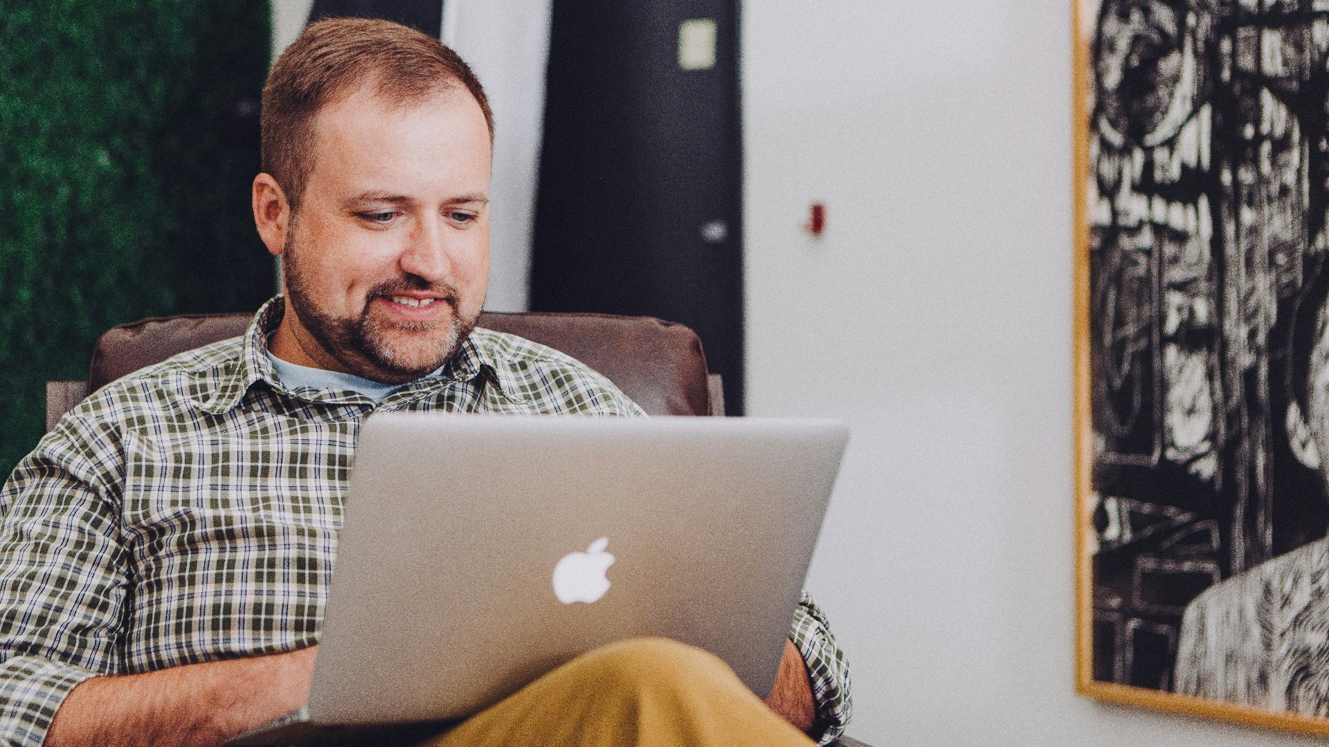 man smiling and using MacBook
