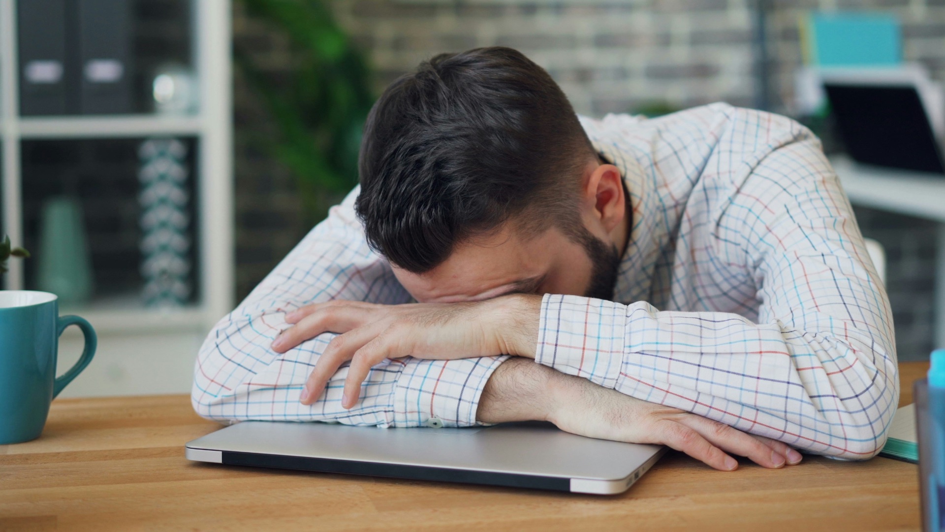 a man sitting at a desk with his head in his hands