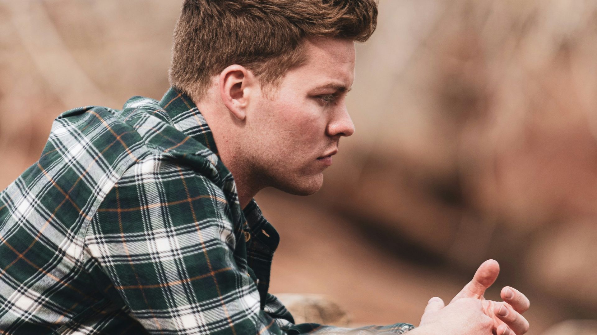 man in black white and gray plaid dress shirt holding smartphone