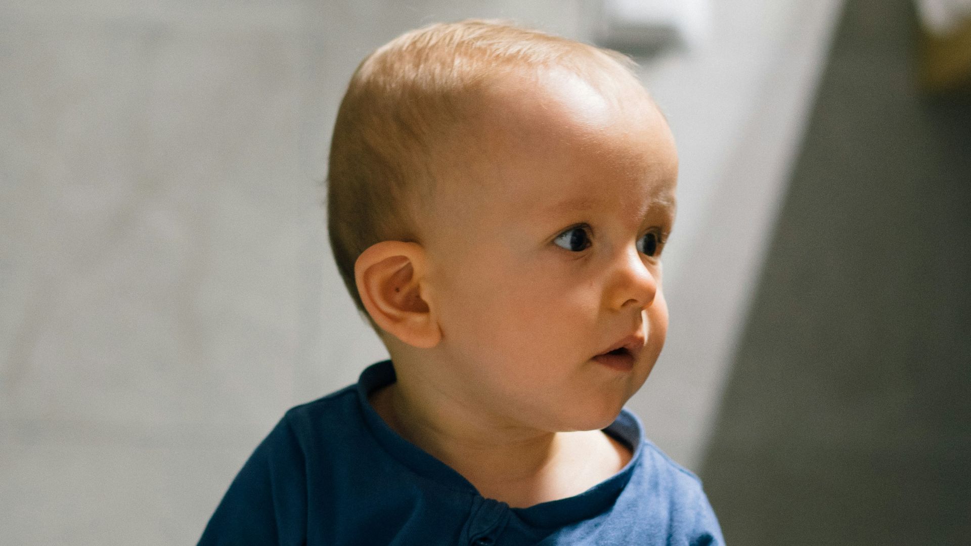 baby in blue long sleeve shirt and blue denim jeans sitting on floor
