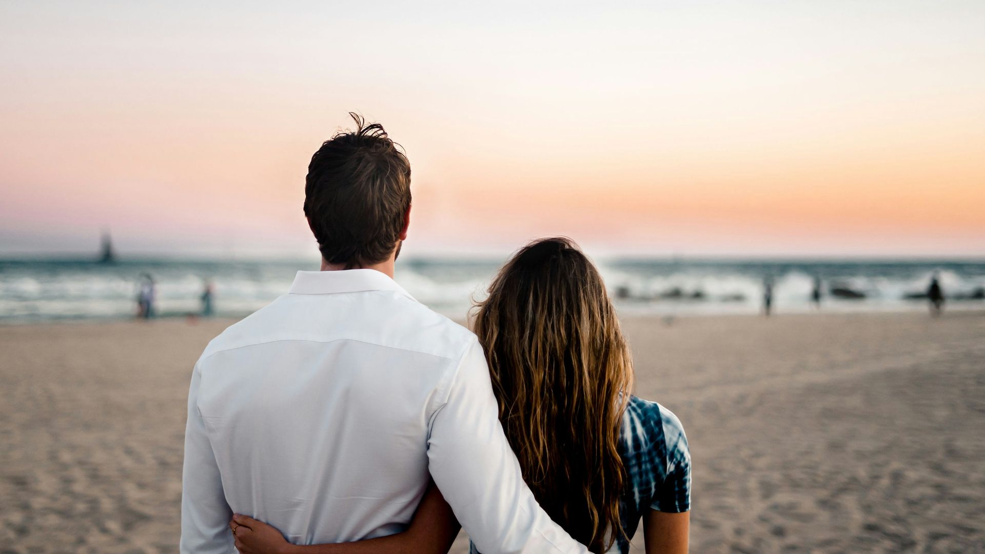 man and woman standing on brown sand during daytime