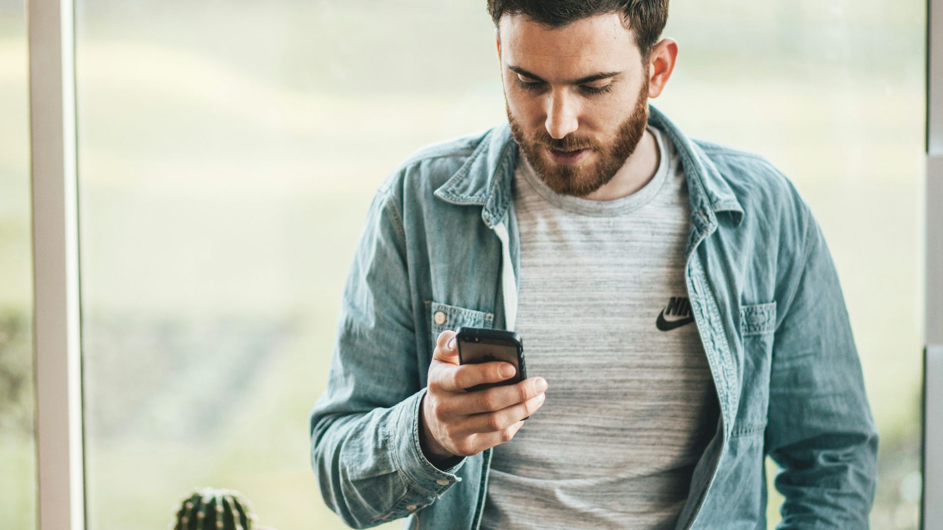 man holding a smartphone near the window