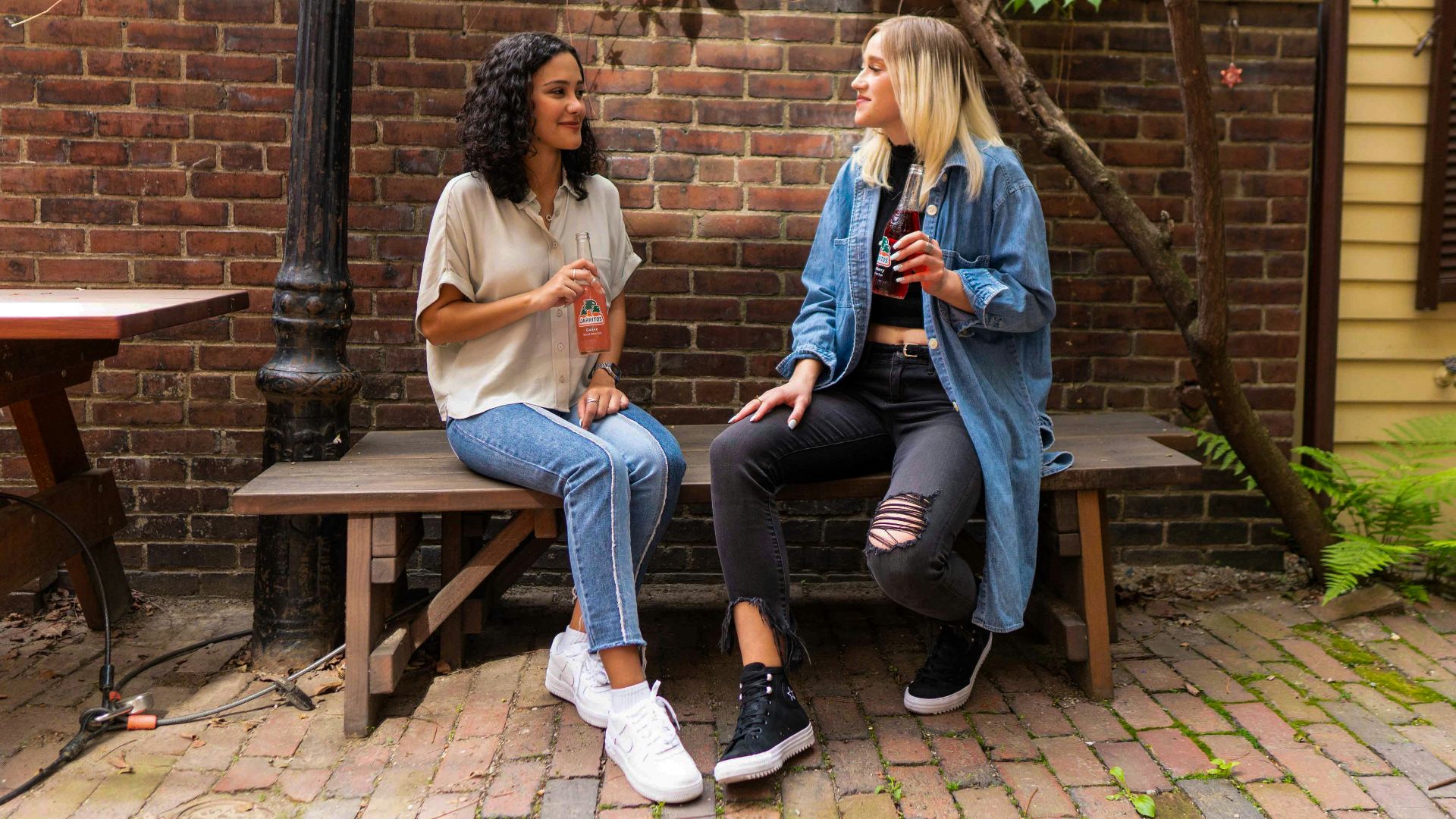 2 women sitting on brown wooden bench