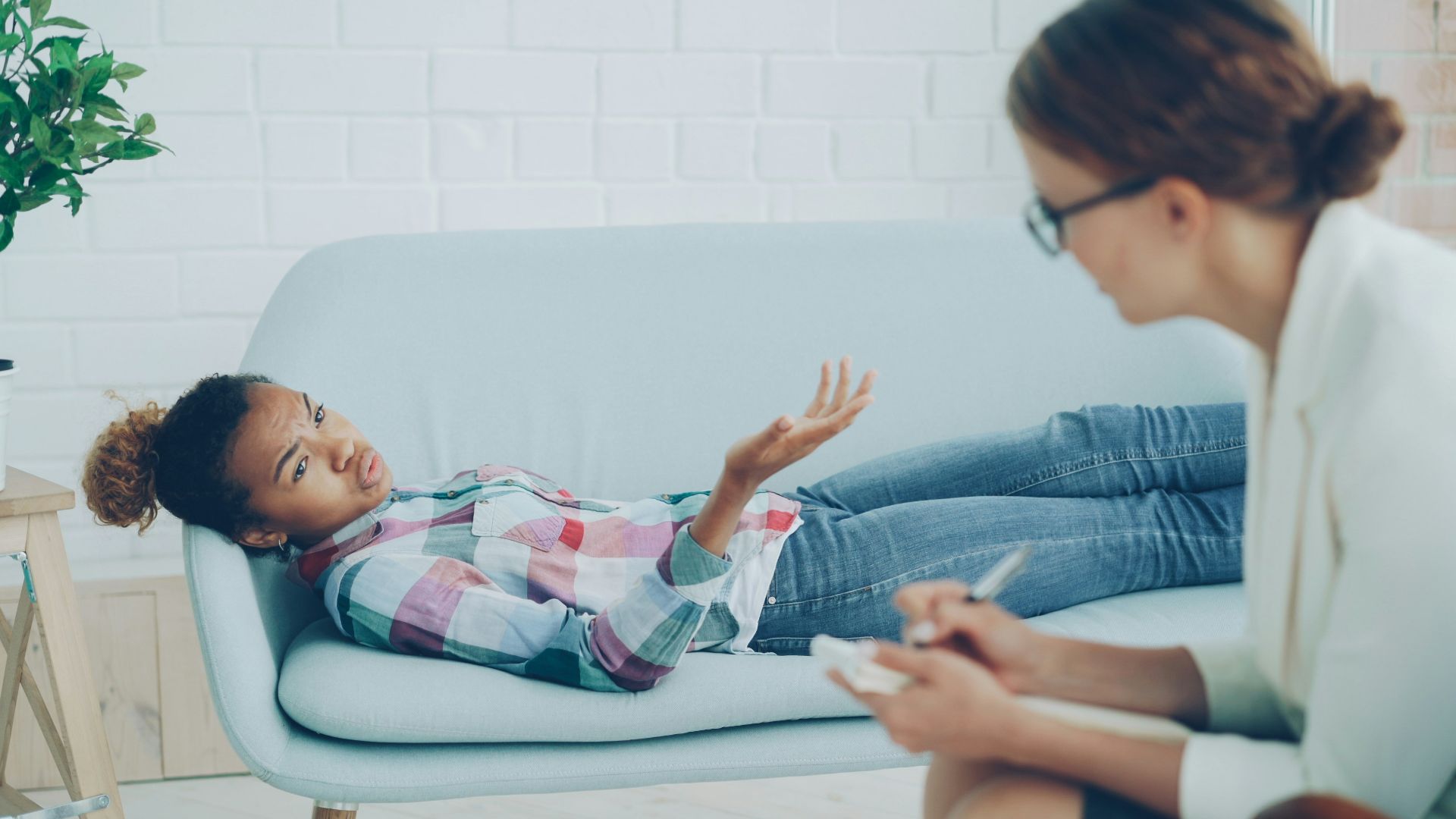 Therapist listens to young woman on couch.